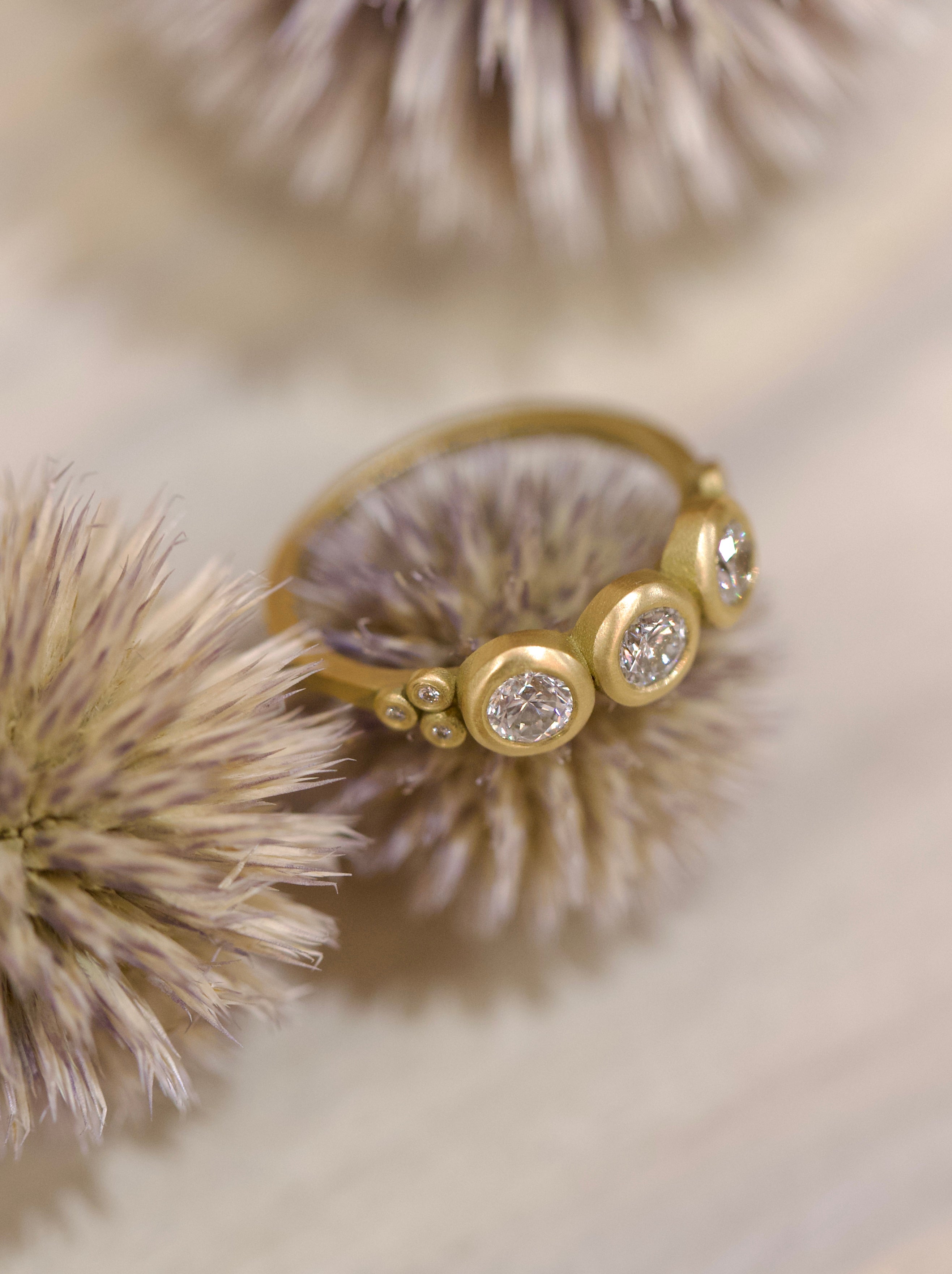 Image of Ananda Khalsa luxury handmade 18k hammered matte gold ring with three 4mm brilliant cut white diamonds delivering timeless elegance