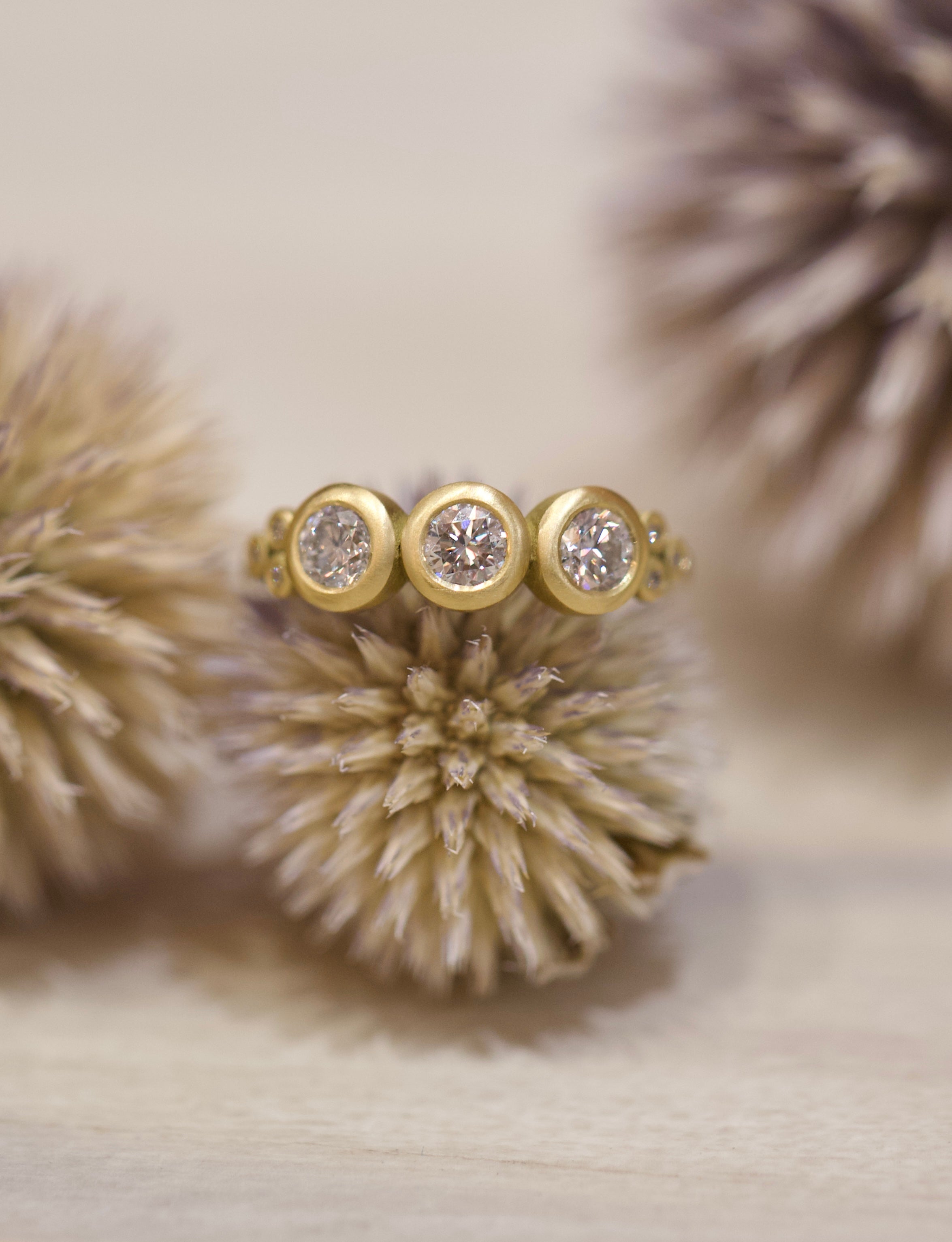 Image of Ananda Khalsa luxury handmade 18k hammered matte gold ring with three 4mm brilliant cut white diamonds delivering timeless elegance