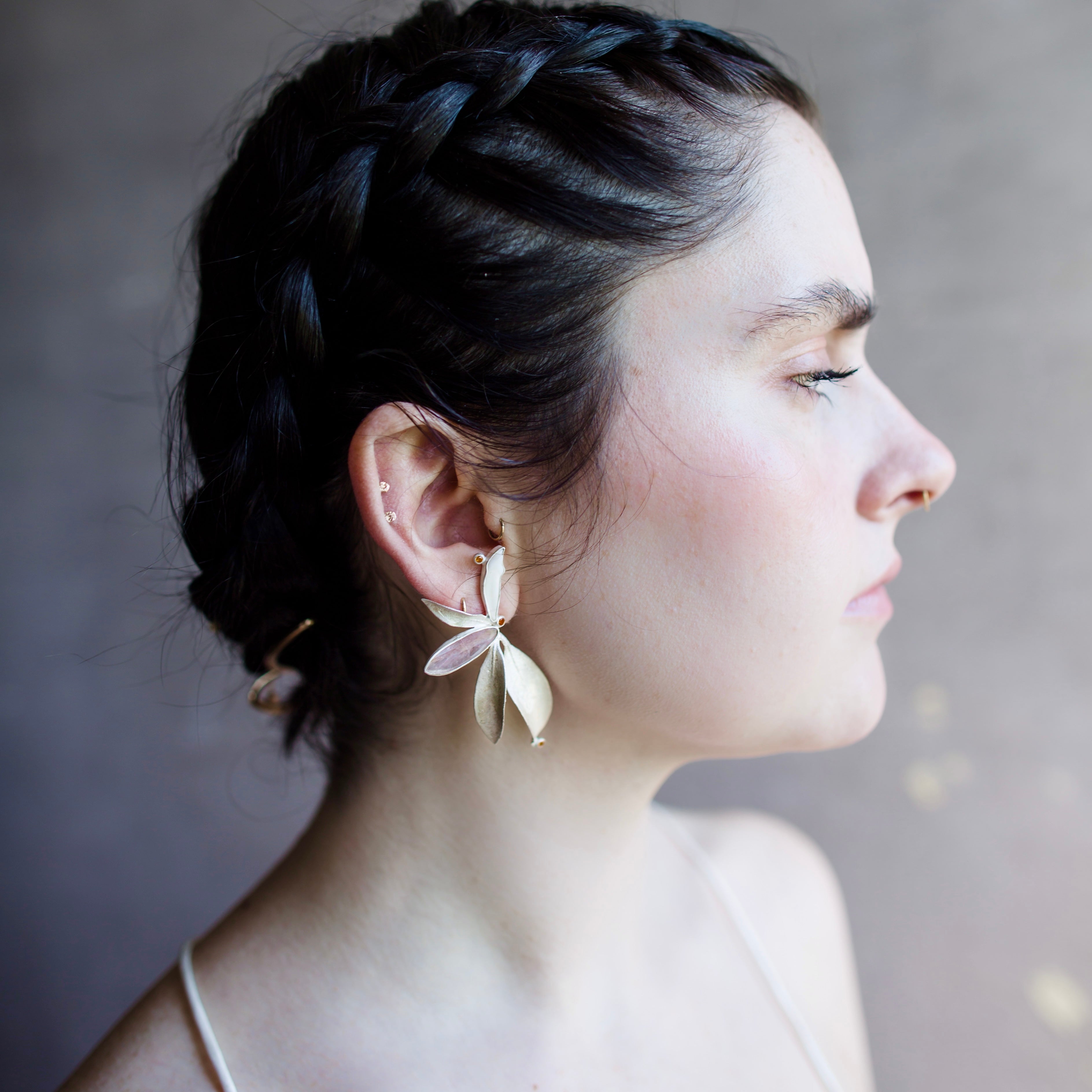 Image featuring a woman wearing North Carolina artist and jeweler Anna Johnson Kalmia Earrings with Teeth, cherry moonstone, topaz, depletion gilded silver, mountain laurel