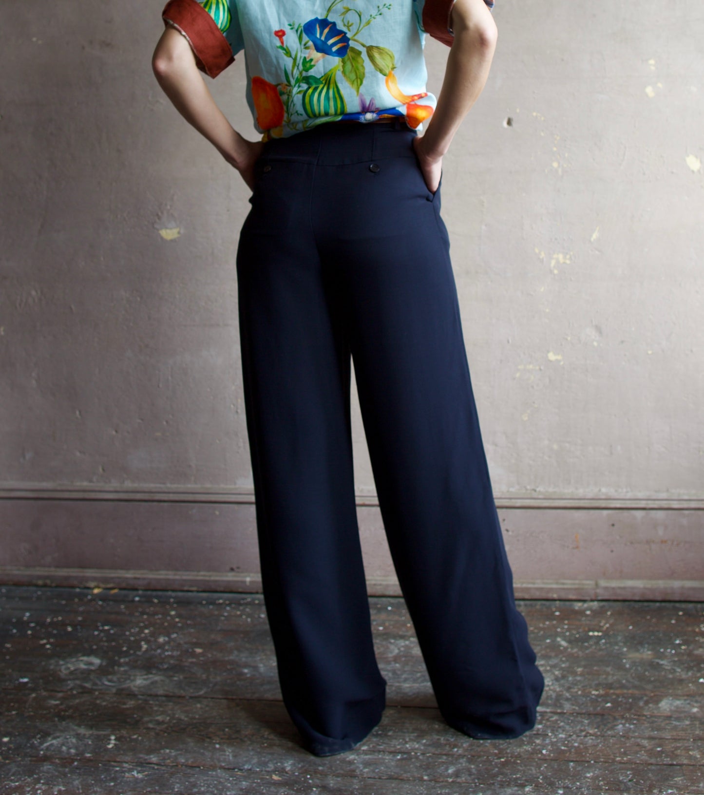 Image of the back of woman wearing the Alemais Dahlia Top and Apiece Apart Cara wide leg pants in navy blue.