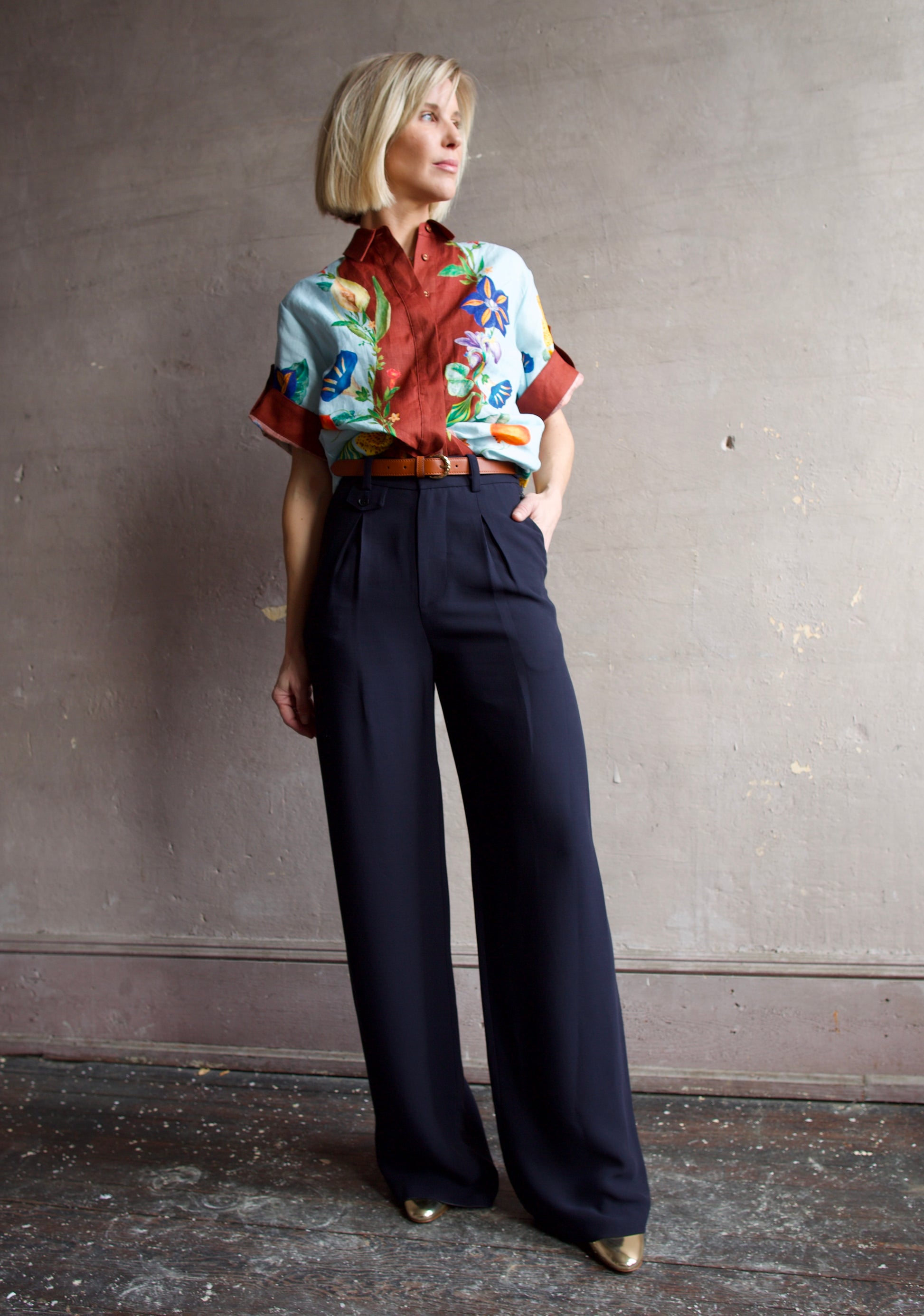 Image of a woman wearing the Alemais Dahlia Top and Apiece Apart Cara wide leg pants in navy blue with the Ulla Johnson Gia belt and Elise shoes.