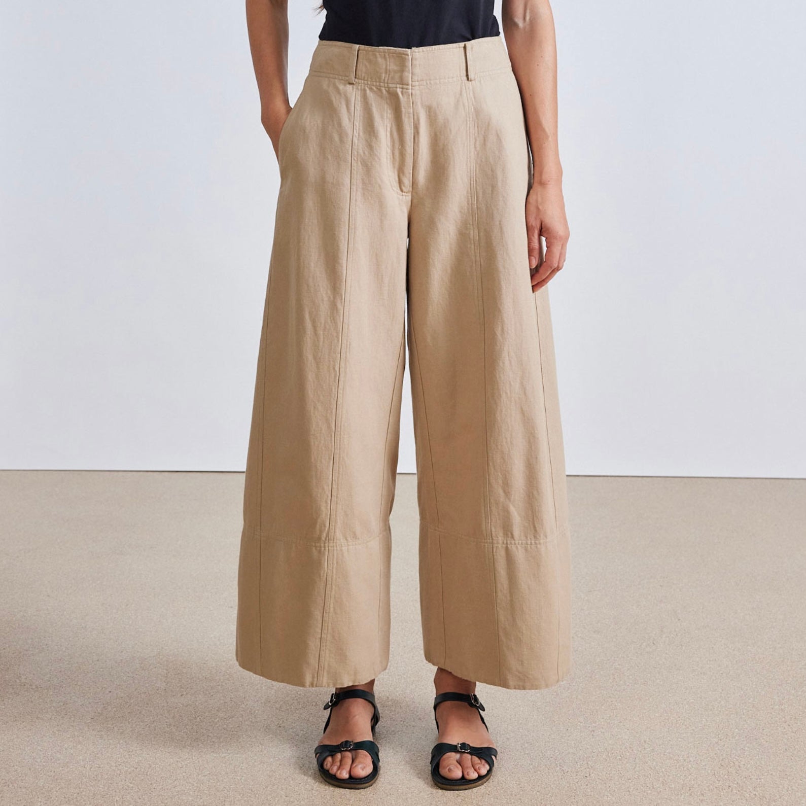 Image featuring a woman wearing the Apiece Apart Malou pants in organic cotton twill with a high-rise, flat front, side slant pockets, back welt pockets, cropped wide leg.