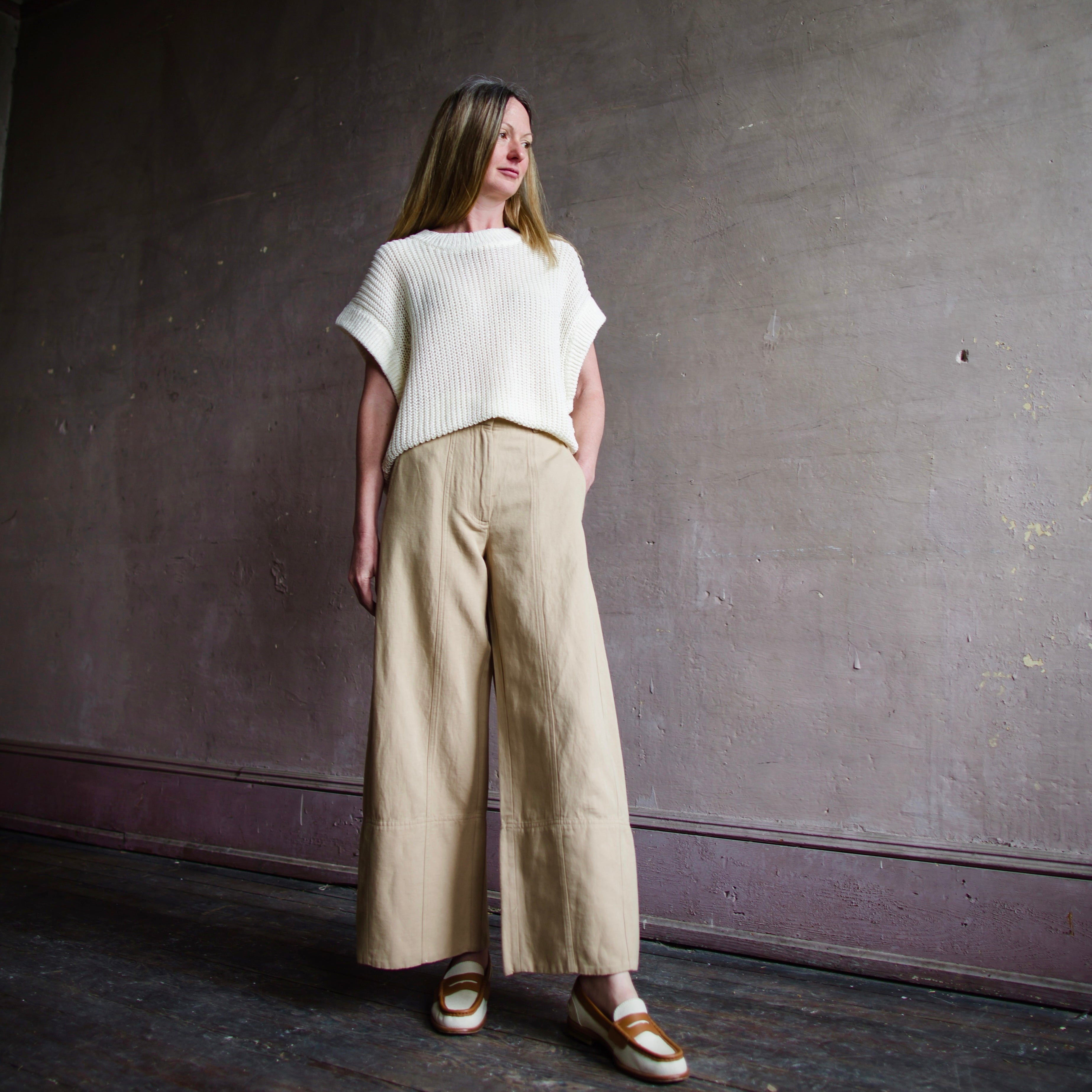 Image featuring a woman wearing the Apiece Apart Malou pants in organic cotton twill with a high-rise, flat front, side slant pockets, back welt pockets, cropped wide leg.