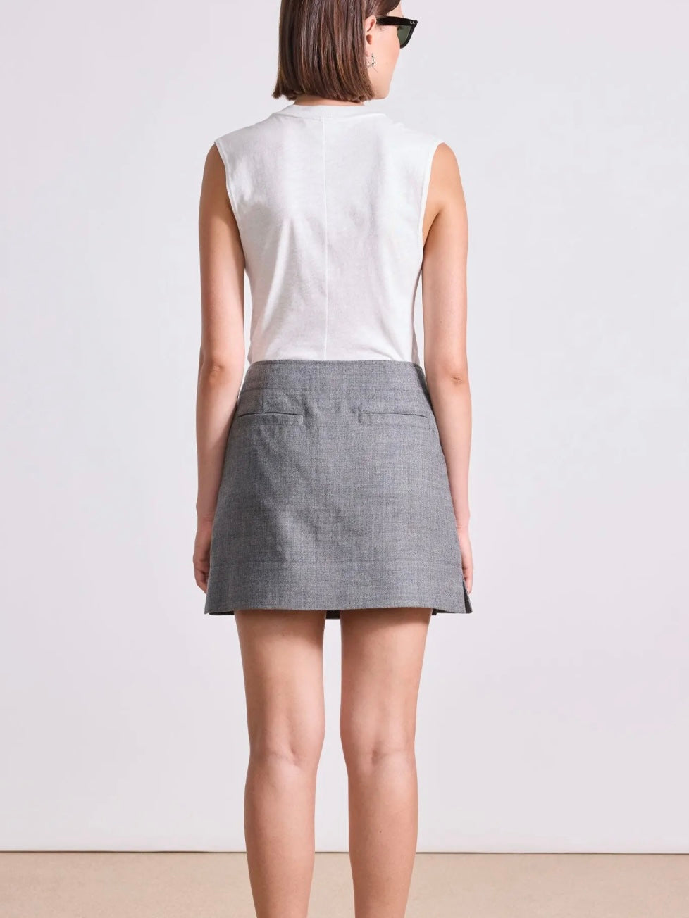 Model wearing Apiece Apart Marta mini skirt in sophisticated neutral heathered grey with back trouser pocket detail