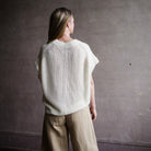 Image featuring a woman wearing the Oliva linen sweater by Apiece Apart with a wide crewneck collar, drop shoulder and ribbed details throughout in cream.