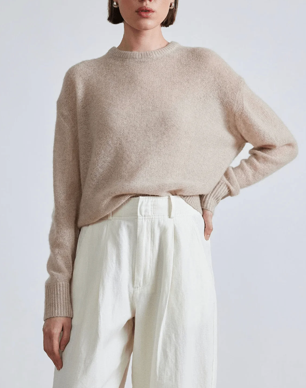 Model wearing Apiece Apart cashmere silk beige tissue weight sweater and white trousers