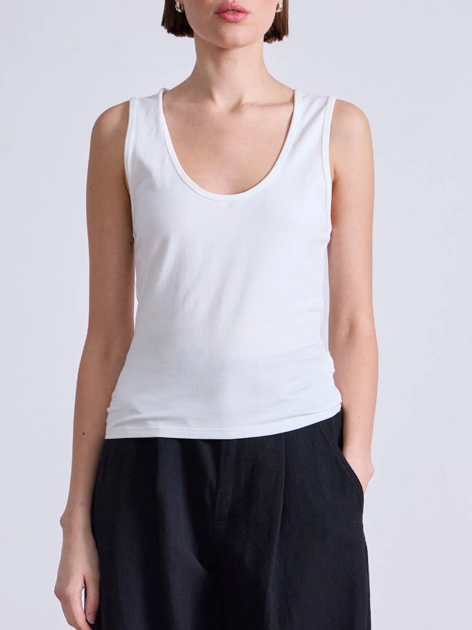Model wearing a white cotton tank top with scoop neck and bra friendly shoulder straps from Apiece Apart