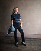 Image featuring a woman wearing the slim Marston corduroy pants by Apiece Apart with a high rise, button front, front patch pockets and a cropped, slightly flared leg in navy blue.