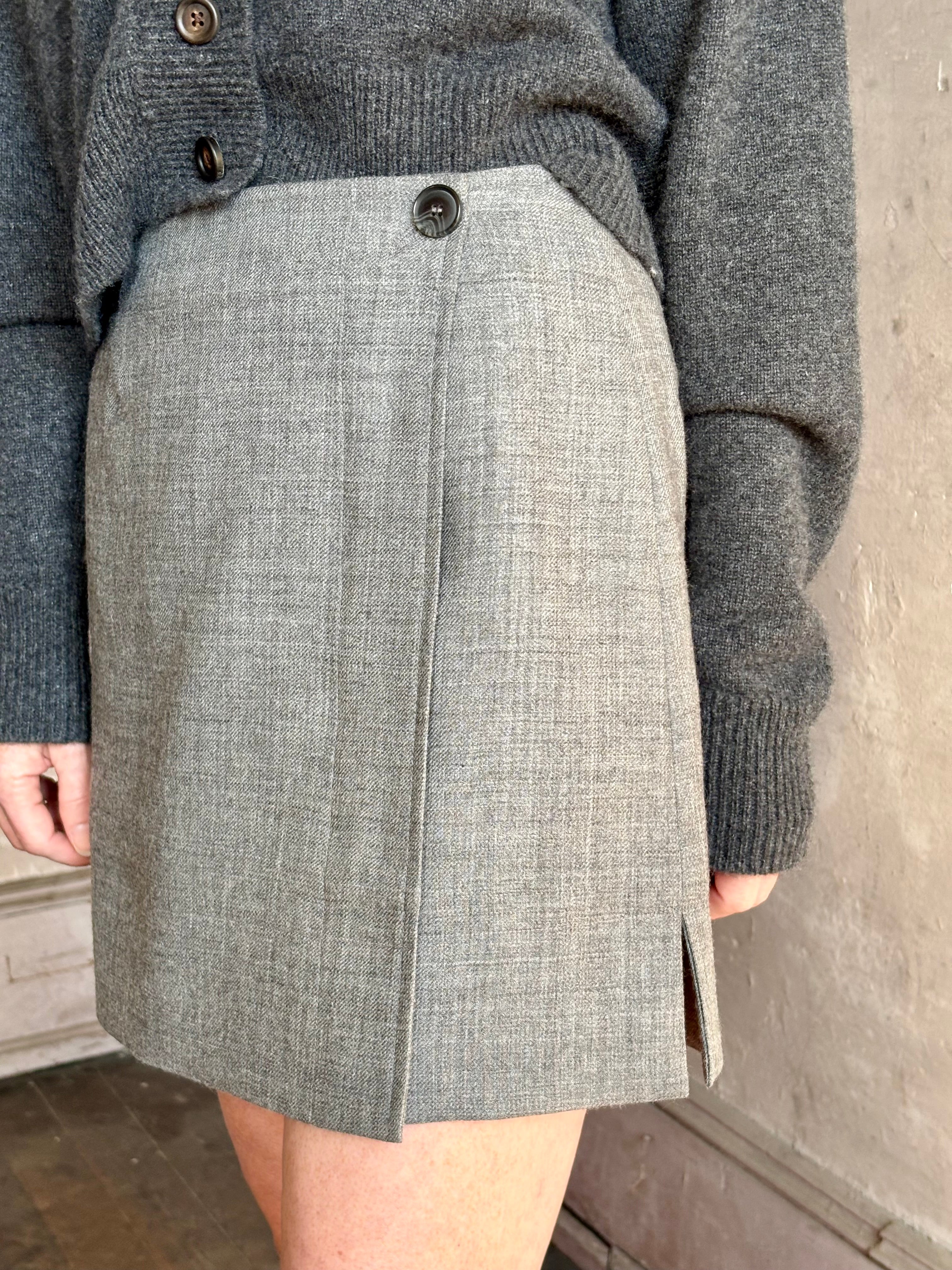 Close up image of mature woman wearing Apiece Apart gray textured Marta mini skirt with a front button closure and side vent tailoring