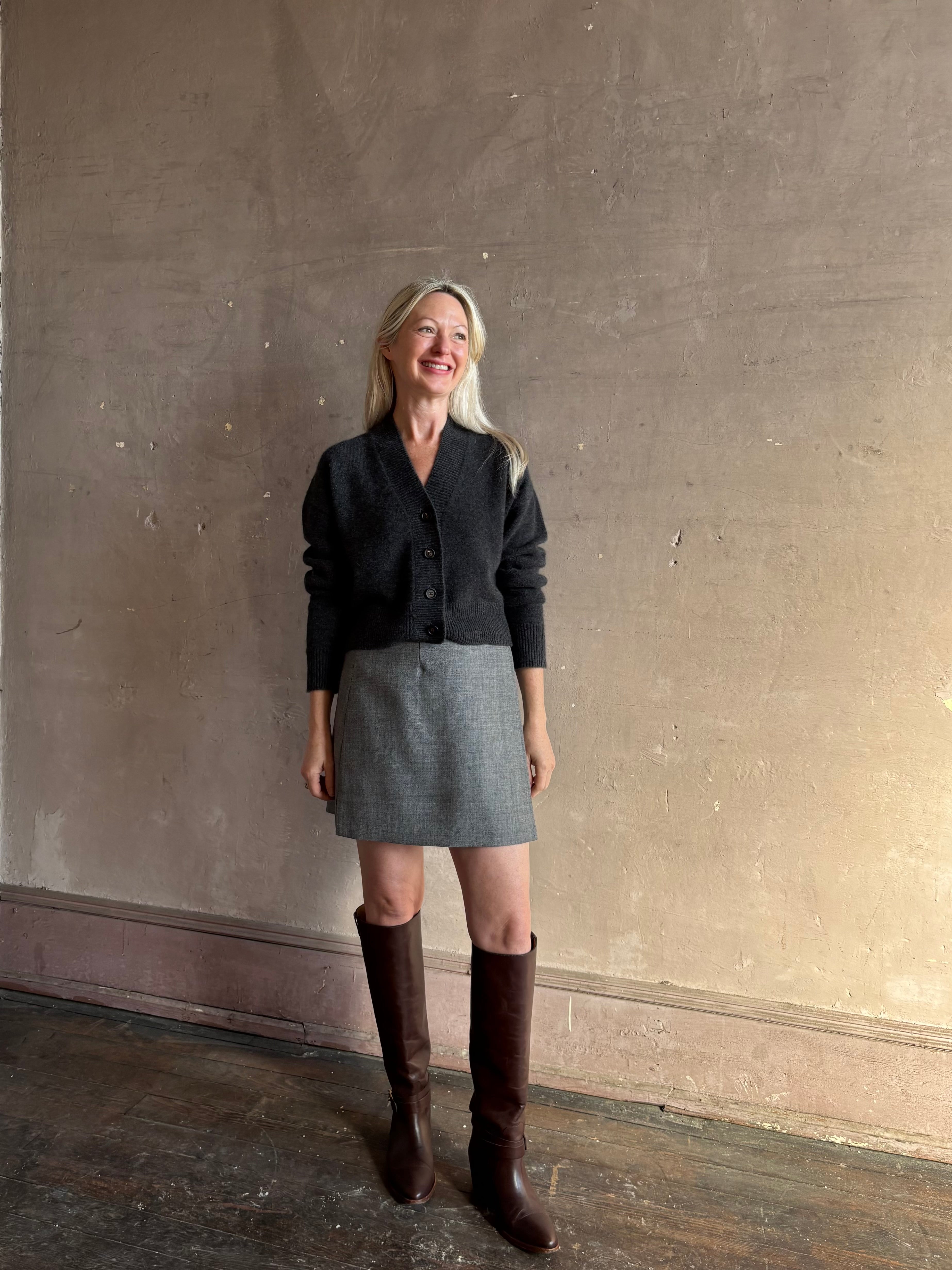 Mature woman wearing Apiece Apart's Marta virgin wool Mini Skirt in Heathered Grey sleek tailored silhouette styled with high boots for Fall