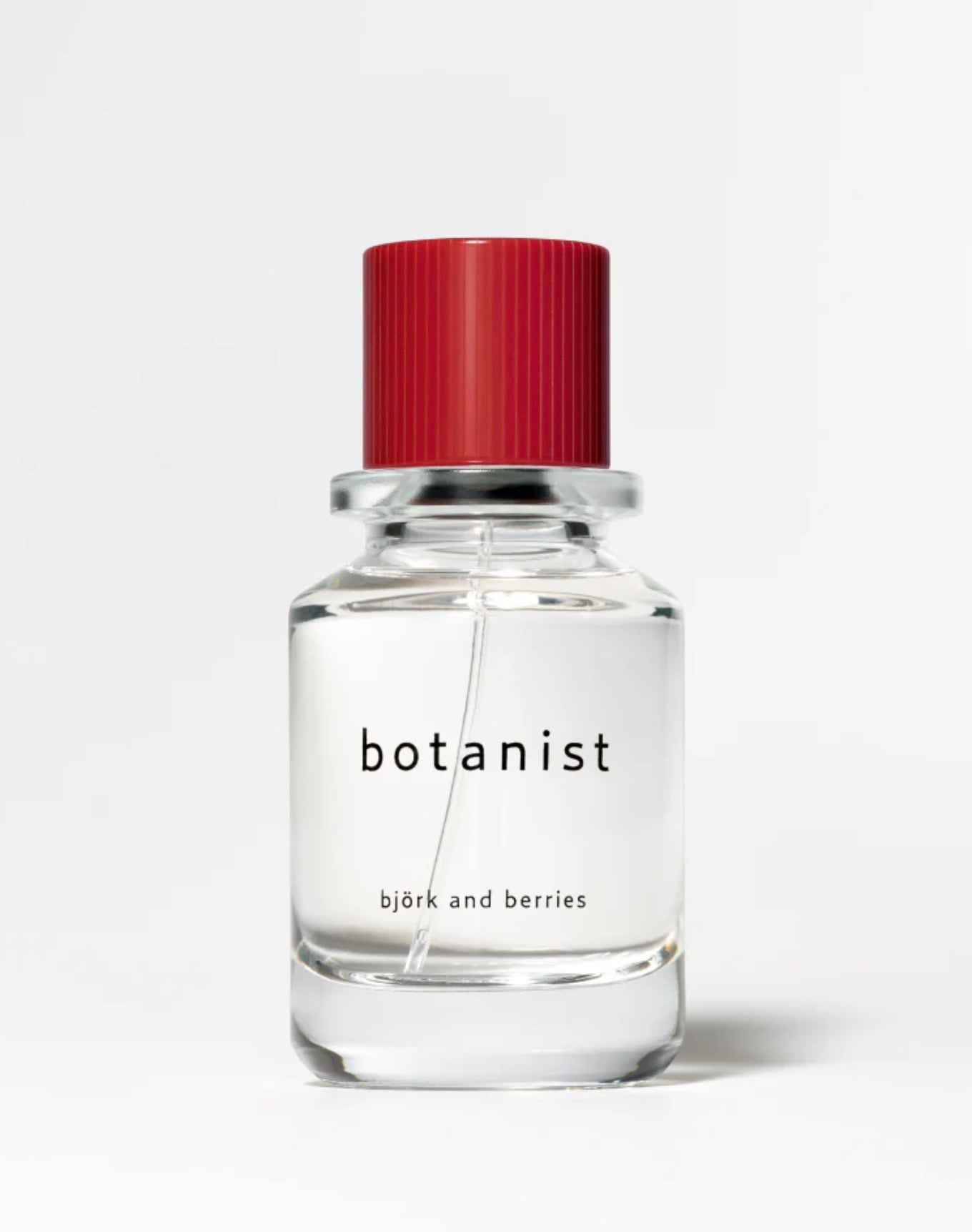 Image of BJORK AND BERRIES Botanist luxury personal fragrance eau de parfum with notes of green apple, vetiver and patchouli in a Scandinavian minimalist design clear glass bottle and red lid