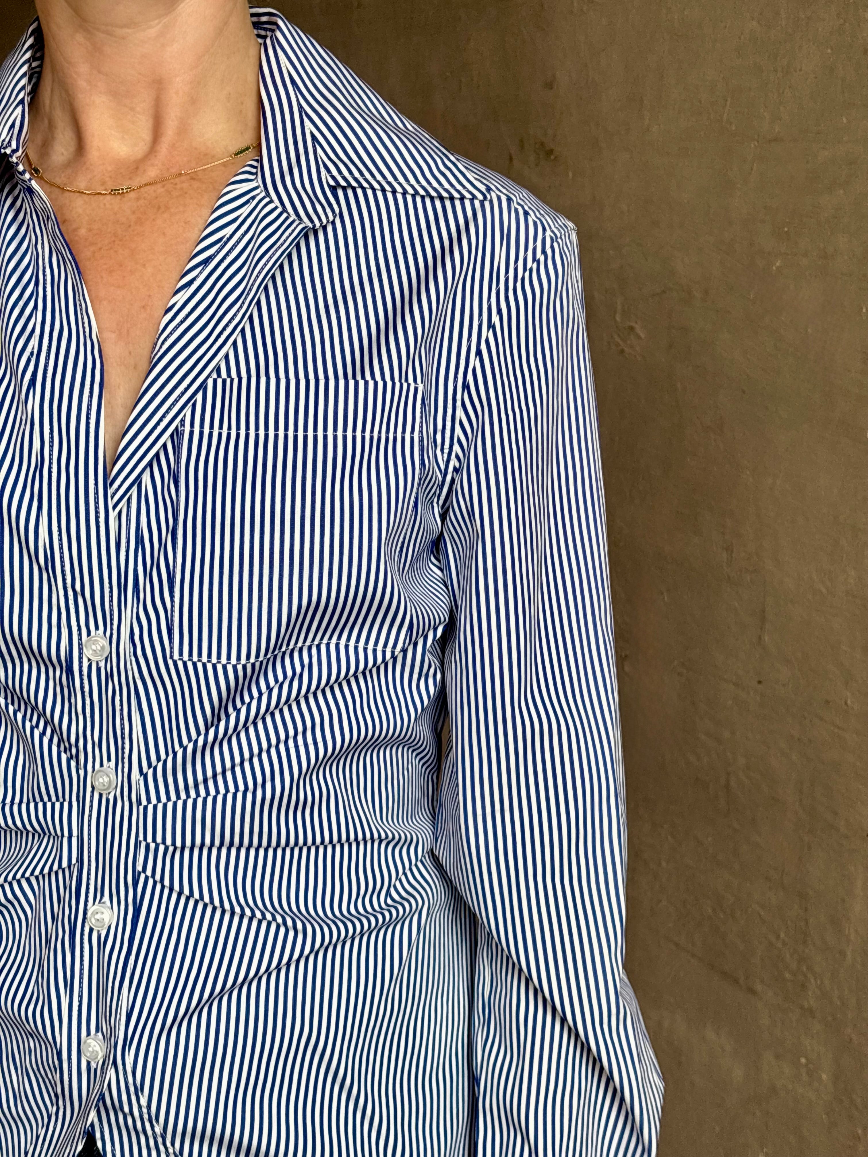 Mature woman wearing the European tailored Sierra Shirt from Callas rendered in a crisp navy and white stripe and crafted from cotton poplin featuring a flattering ruched front , long sleeves, v-neck and rounded bottom detail