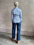 Mature woman wearing the European tailored Sierra Shirt from Callas rendered in a crisp navy and white stripe and crafted from cotton poplin featuring a flattering ruched front , long sleeves, v-neck and rounded bottom detail