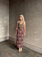 Mature woman wearing Cara Cara blaze long pencil skirt with a brown pink and beige botanical damask pattern 