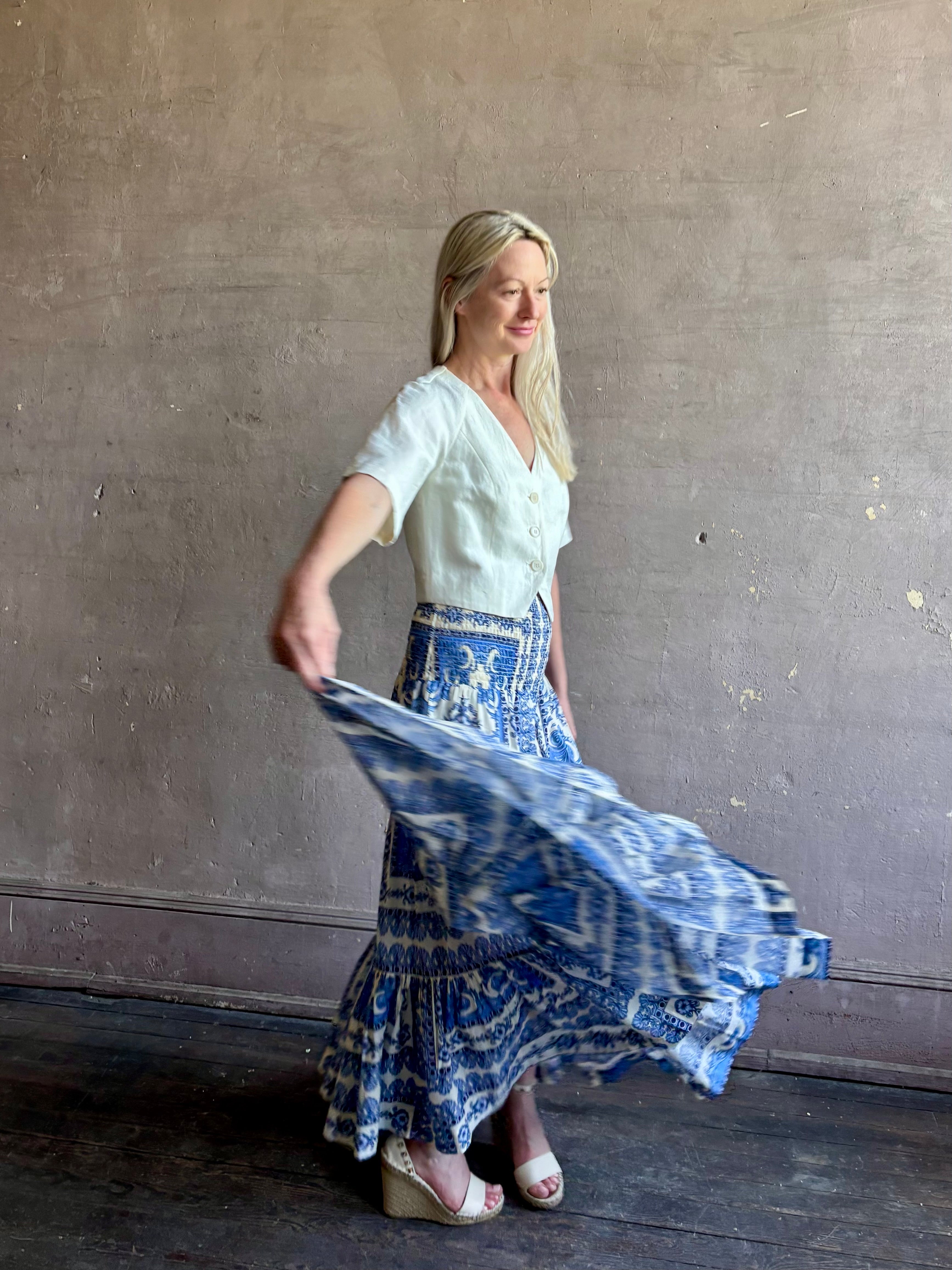 Mature woman wearing Emilia Skirt from Cara Cara rendered in the Hudson Scarf Sky blue and white print crafted from 100% cotton with shirred drop waist and ruffled tiered full skirt