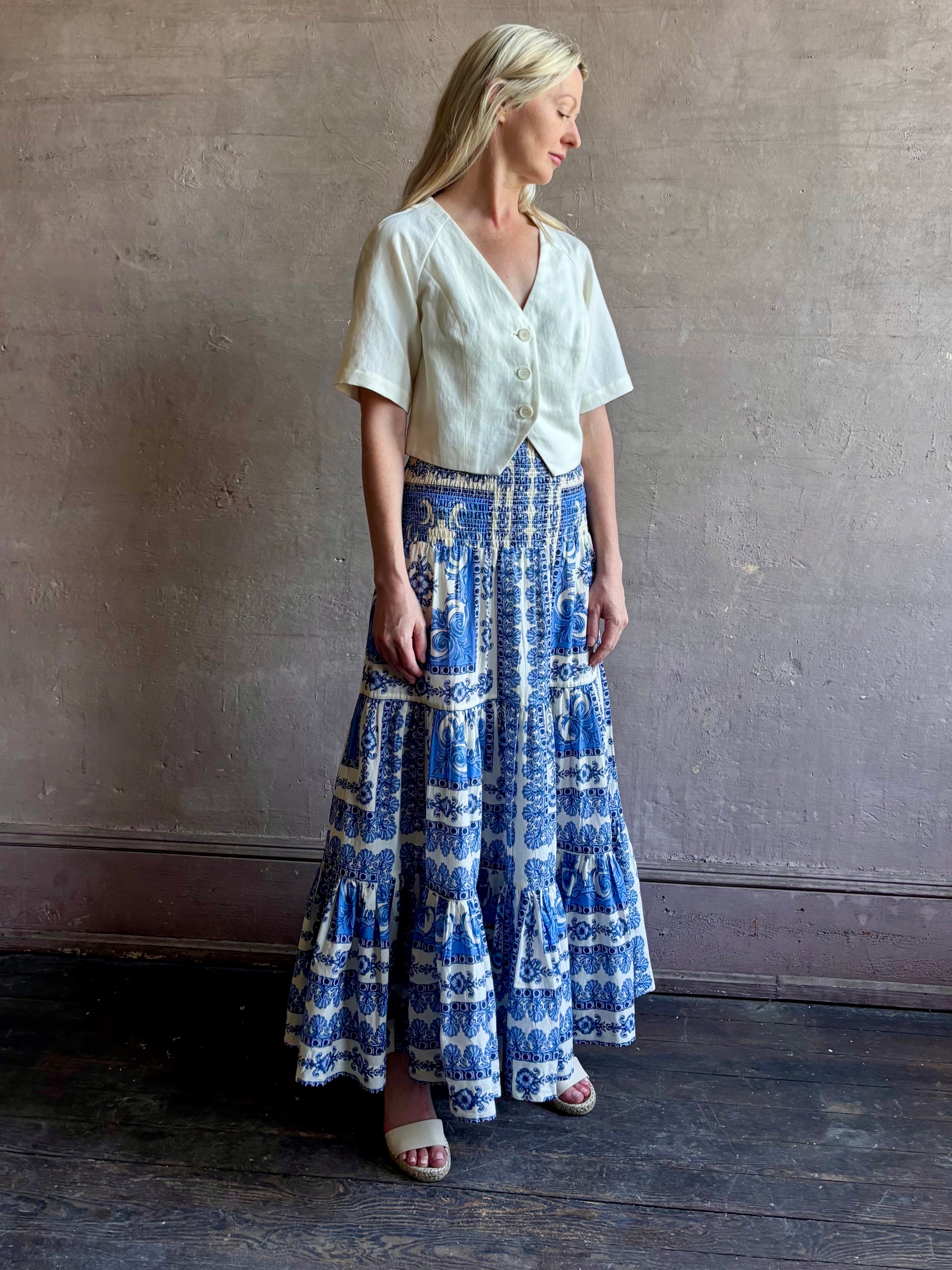 Mature woman wearing Emilia Skirt from Cara Cara rendered in the Hudson Scarf Sky blue and white print crafted from 100% cotton with shirred drop waist and ruffled tiered full skirt