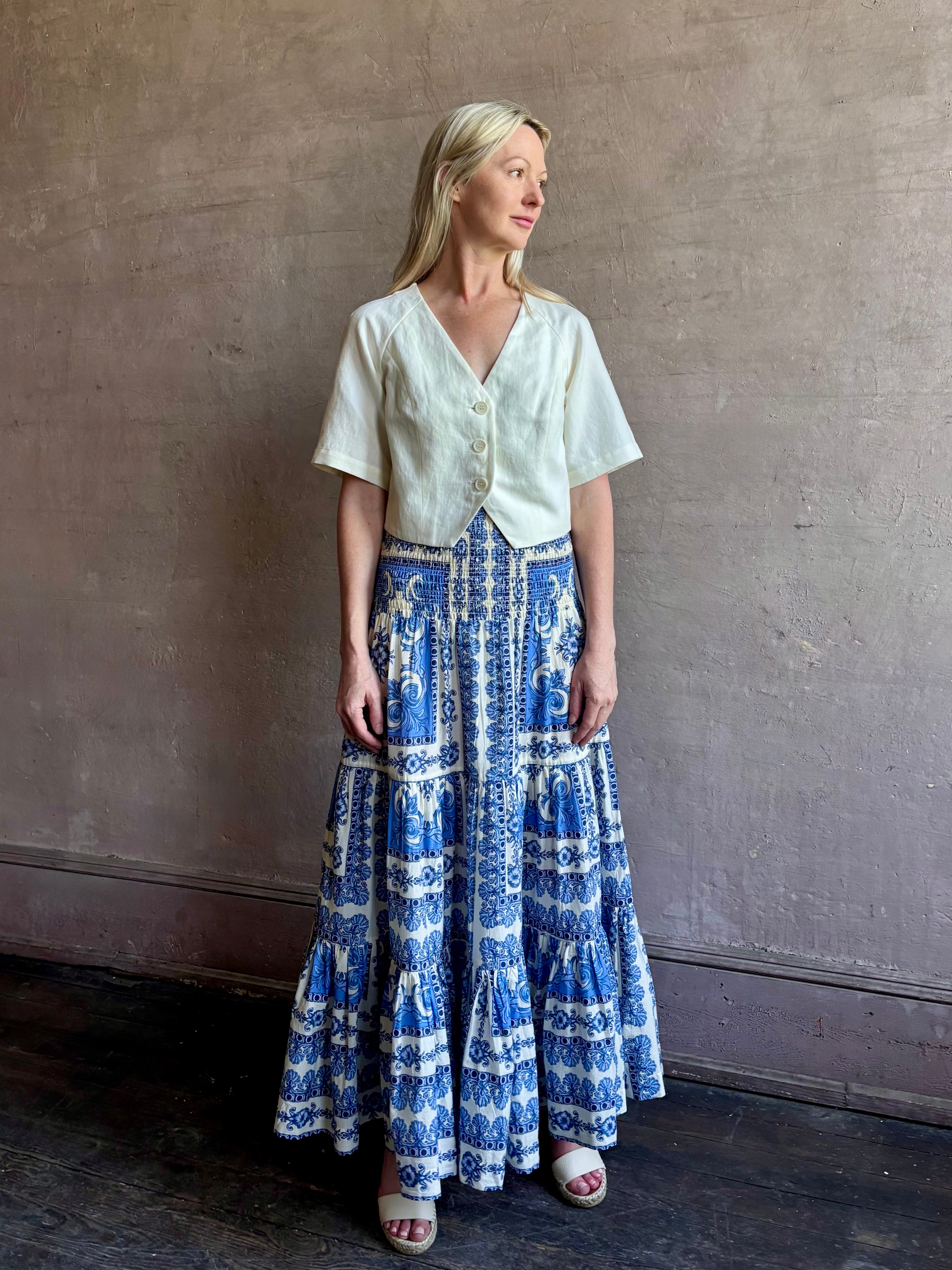 Mature woman wearing Emilia Skirt from Cara Cara rendered in the Hudson Scarf Sky blue and white print crafted from 100% cotton with shirred drop waist and ruffled tiered full skirt