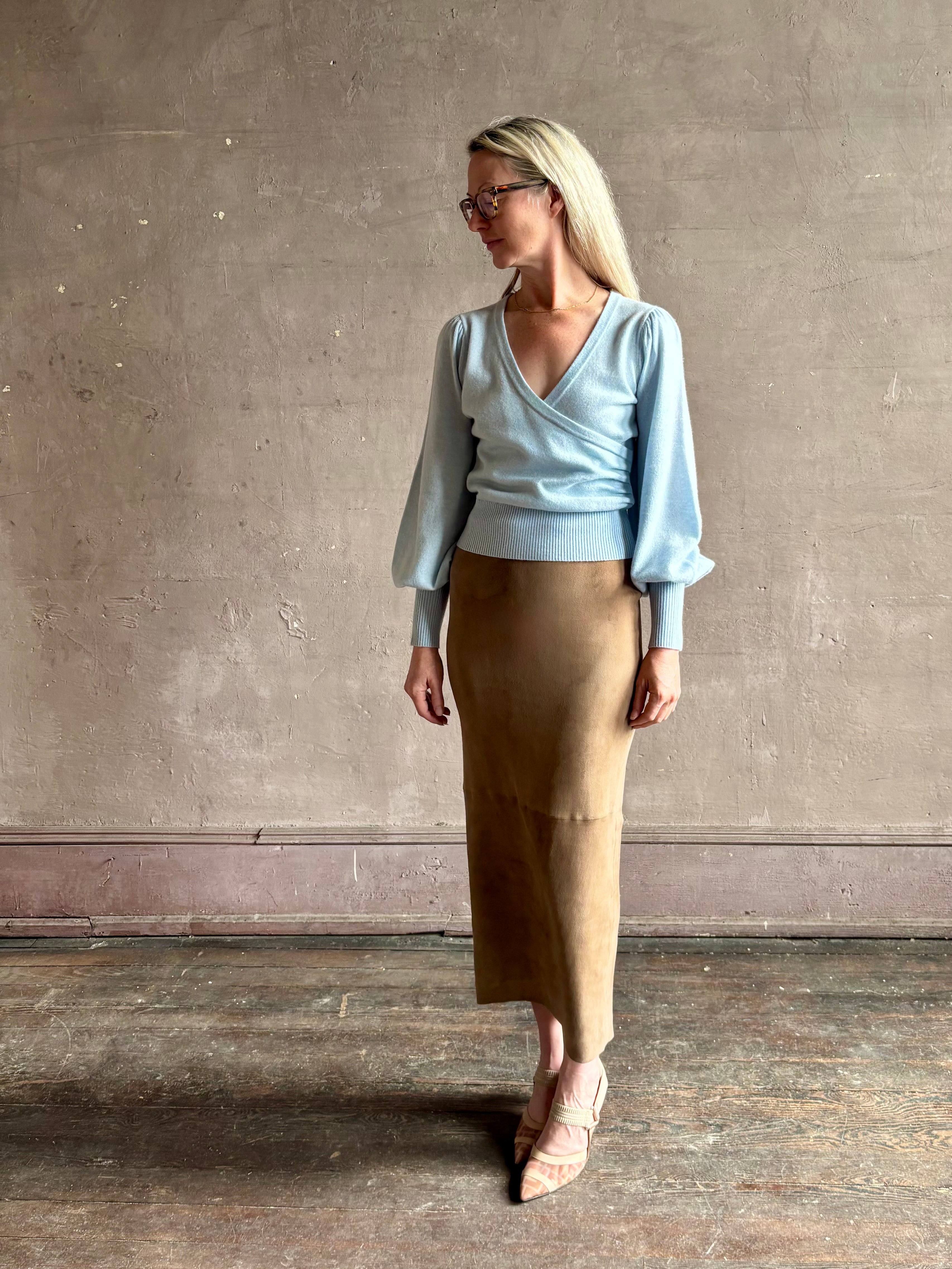 mature woman wearing designer Cara Cara wool-cashmere blend light blue wrap sweater v-neck and long sleeves