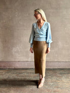 mature woman wearing designer Cara Cara wool-cashmere blend light blue wrap sweater v-neck and long sleeves