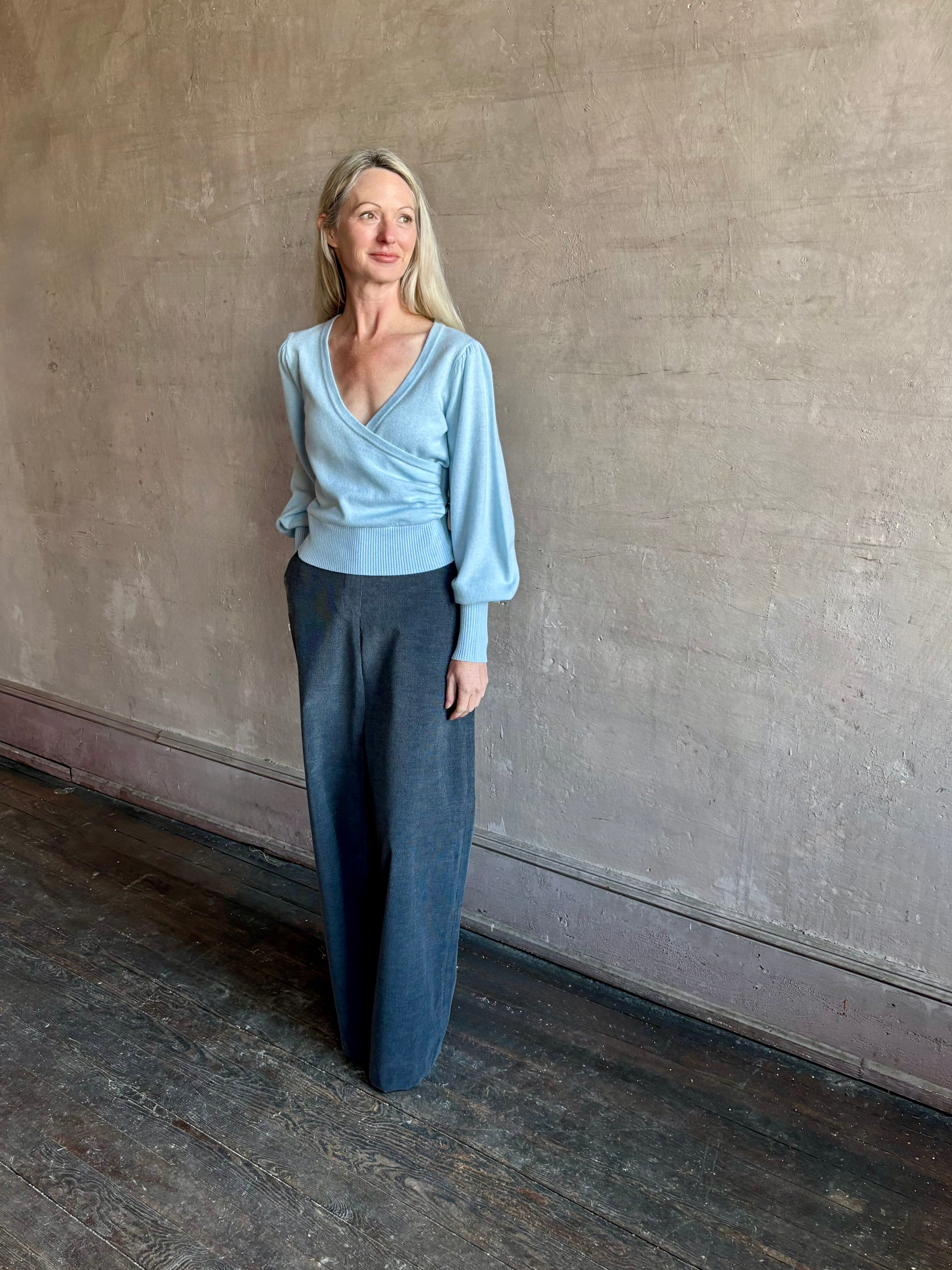 Image of mature woman wearing designer Cara Cara wool-cashmere blend light blue wrap sweater with a v-neck and long sleeves