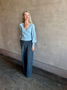 Image of mature woman wearing designer Cara Cara wool-cashmere blend light blue wrap sweater with a v-neck and long sleeves