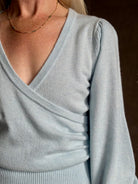 mature woman wearing designer Cara Cara wool-cashmere blend light blue wrap sweater v-neck and long sleeves