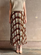 Mature woman wearing designer Cara Cara brown, cream, and green plaid patterned pleated otta maxi skirt