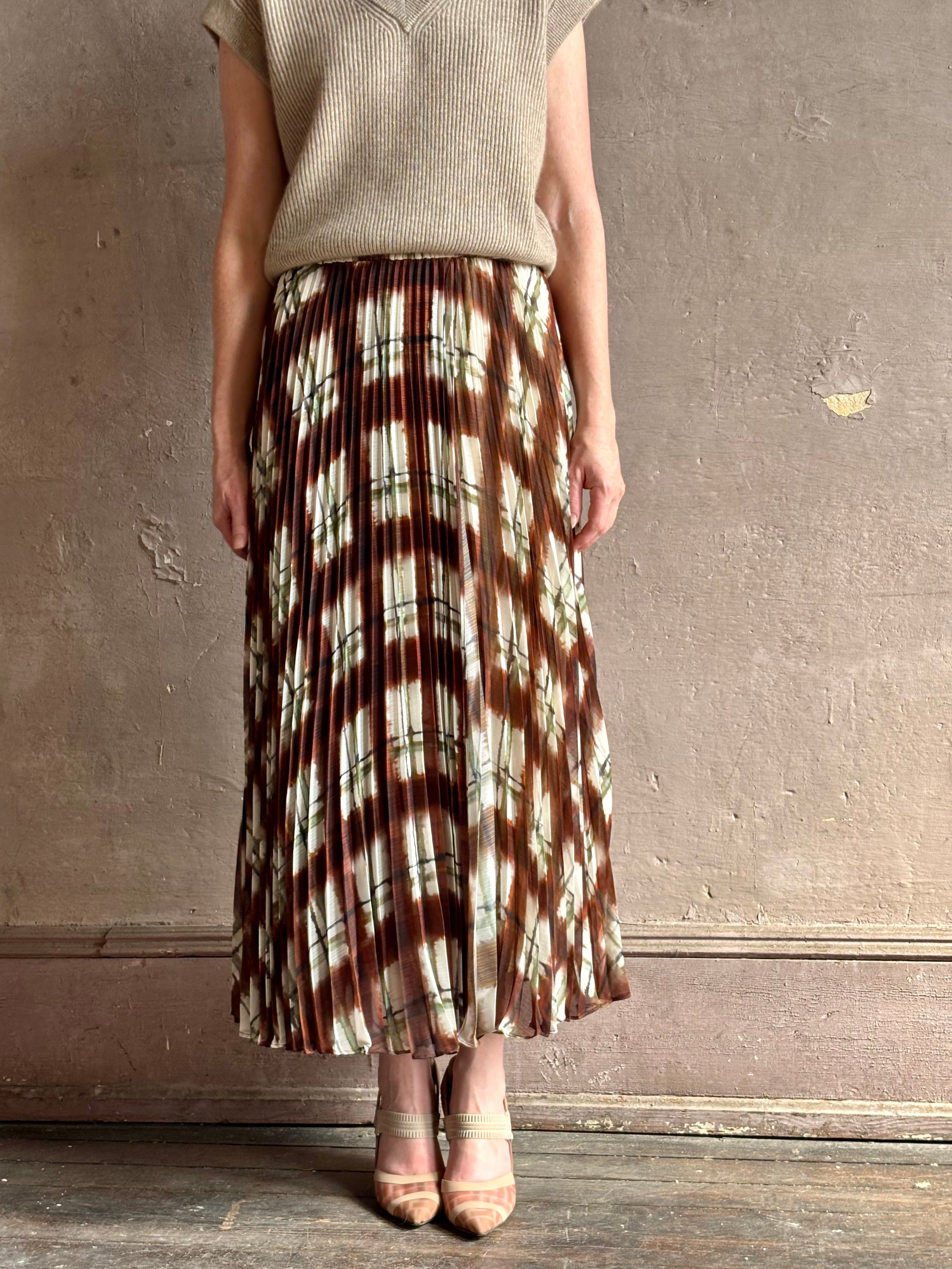 Mature woman wearing designer Cara Cara brown, cream, and green plaid patterned pleated otta maxi skirt
