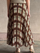 Mature woman wearing designer Cara Cara brown, cream, and green plaid patterned pleated otta maxi skirt