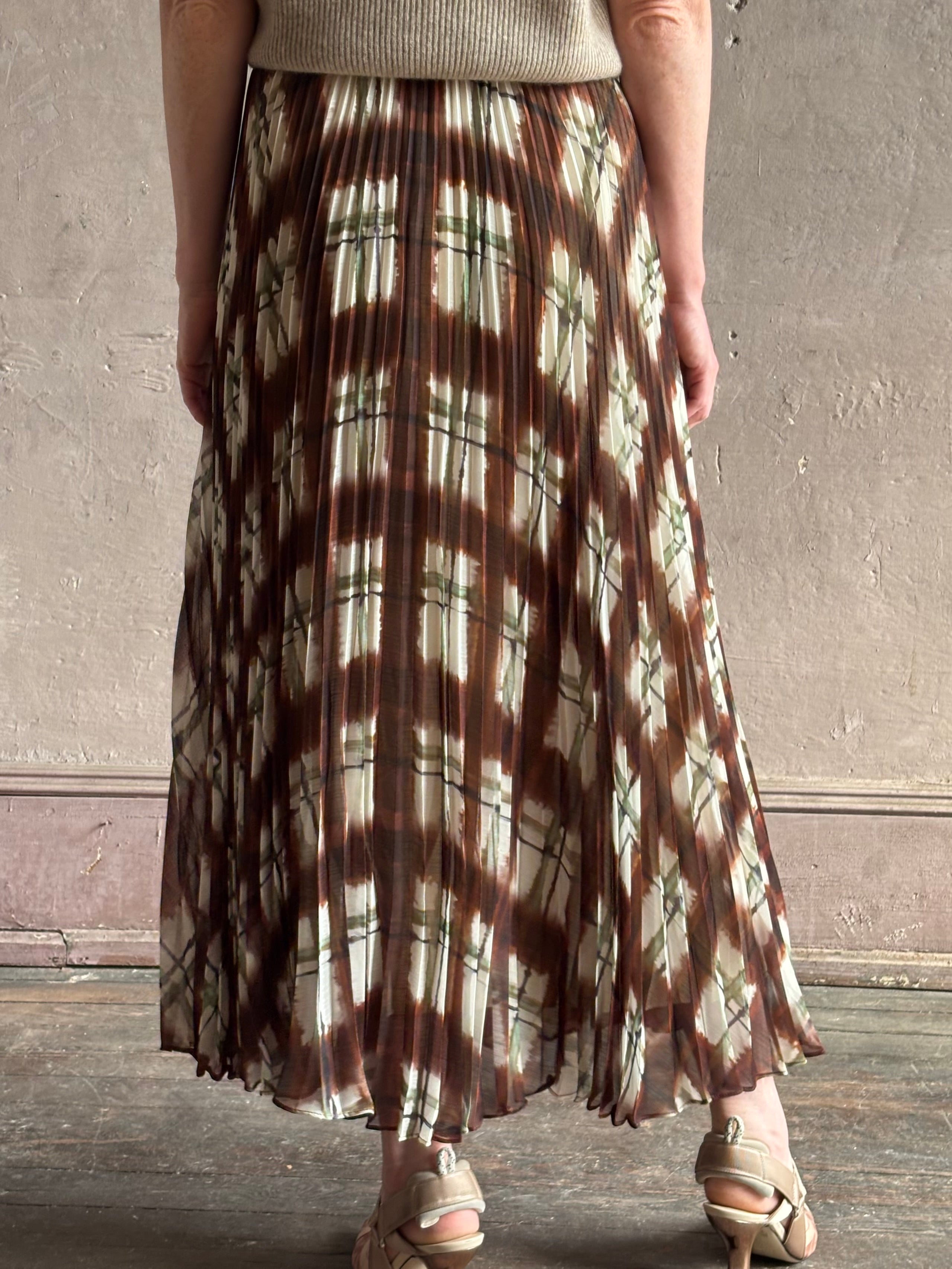 Mature woman wearing designer Cara Cara brown, cream, and green plaid patterned pleated otta maxi skirt