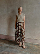 Mature woman wearing designer Cara Cara brown, cream, and green plaid patterned pleated otta maxi skirt