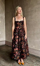 Image of woman wearing premium linen-silk Pheobe midi dress by Cara Cara with expertly crafted unlined corset bodice in an elegant black floral print