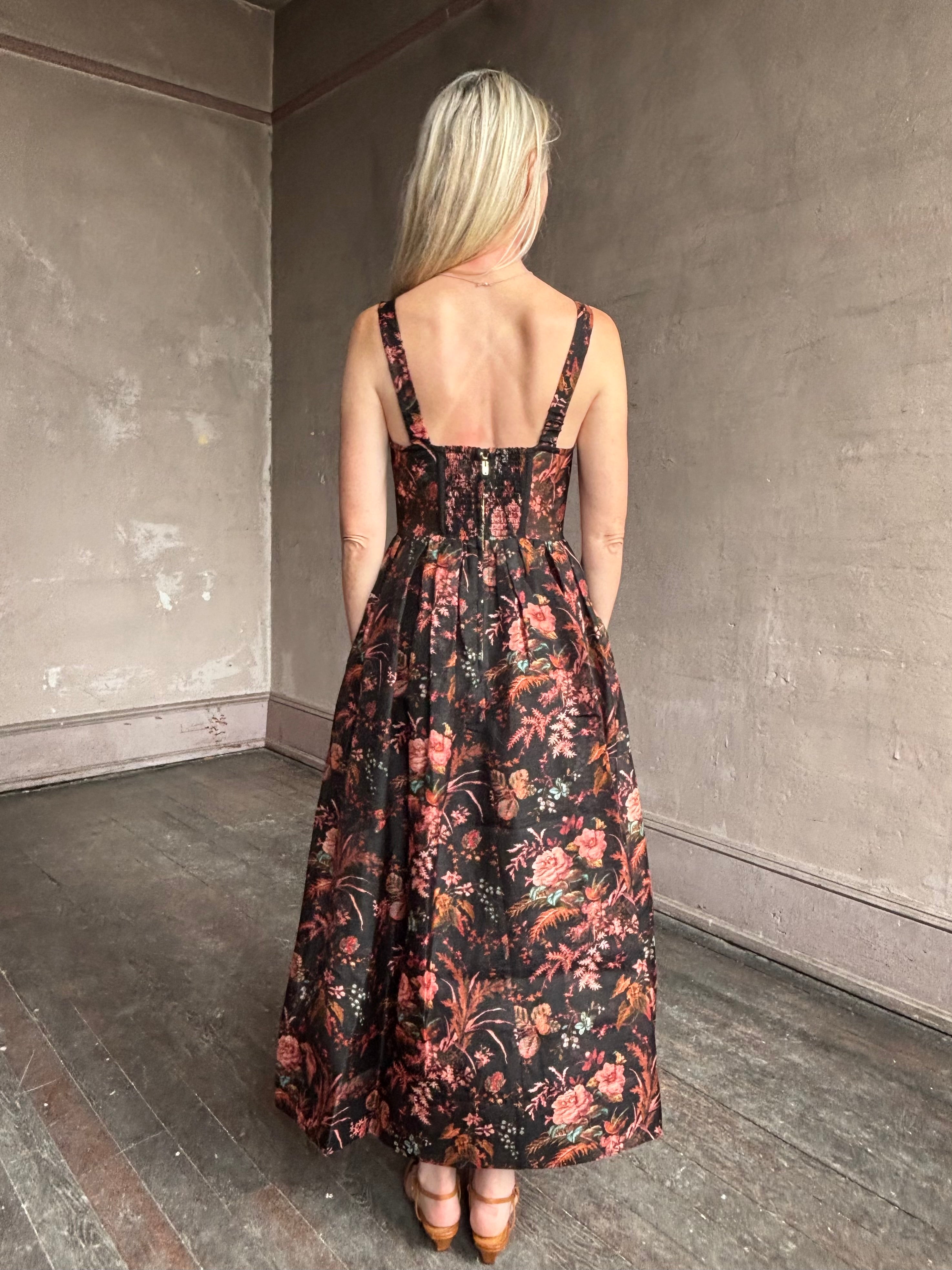Image of woman wearing premium linen-silk Pheobe midi dress by Cara Cara with expertly crafted unlined corset bodice in an elegant black floral print