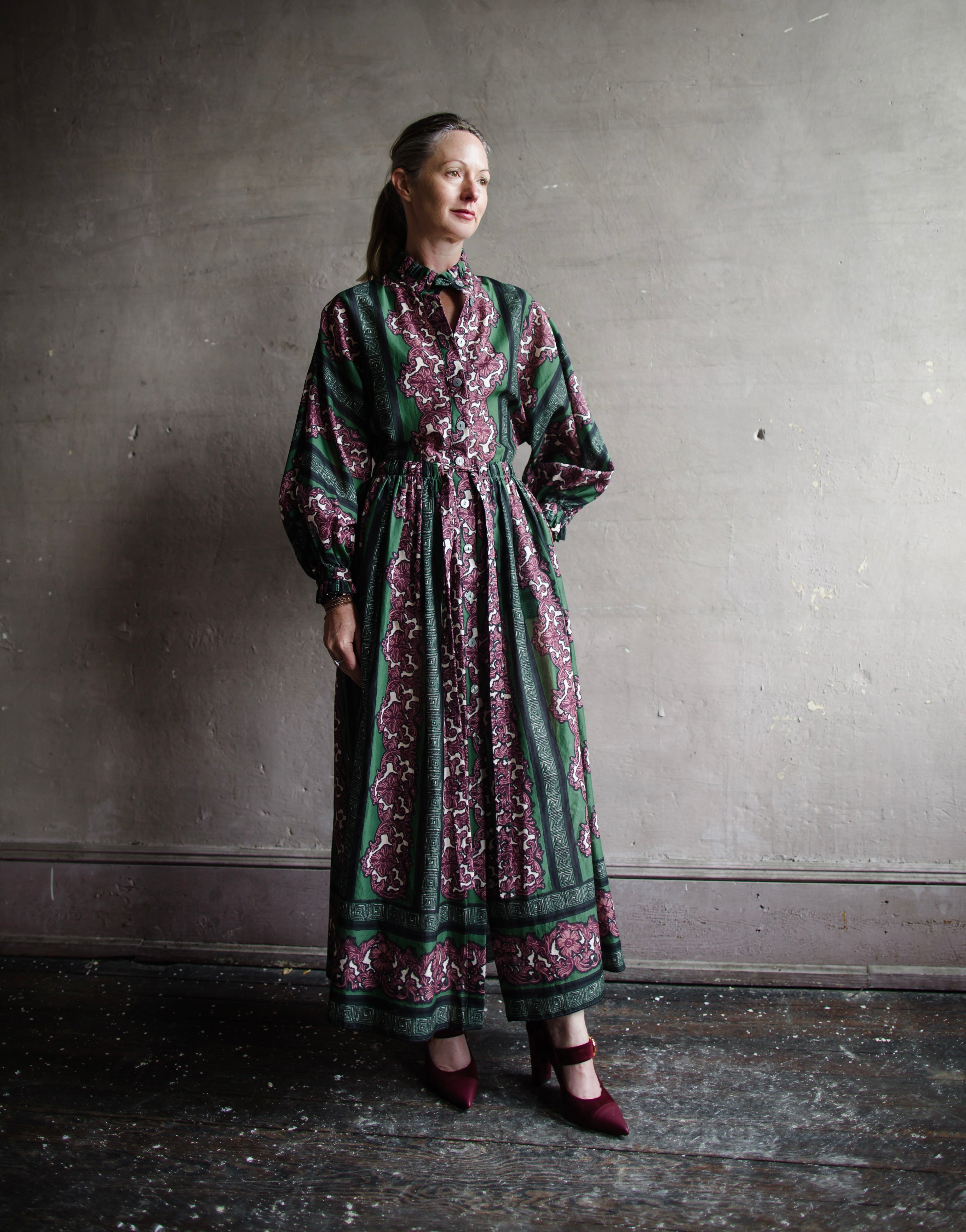 Image features woman wearing Cara Cara Beatrice Dress. This dress is full length with long sleeves and a drawstring waist. 