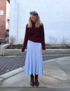 Mature woman wearing designer Cara Cara dara skirt in sky blue in flattering fit and flare sihlouette perfect layering with a heavy fall sweater