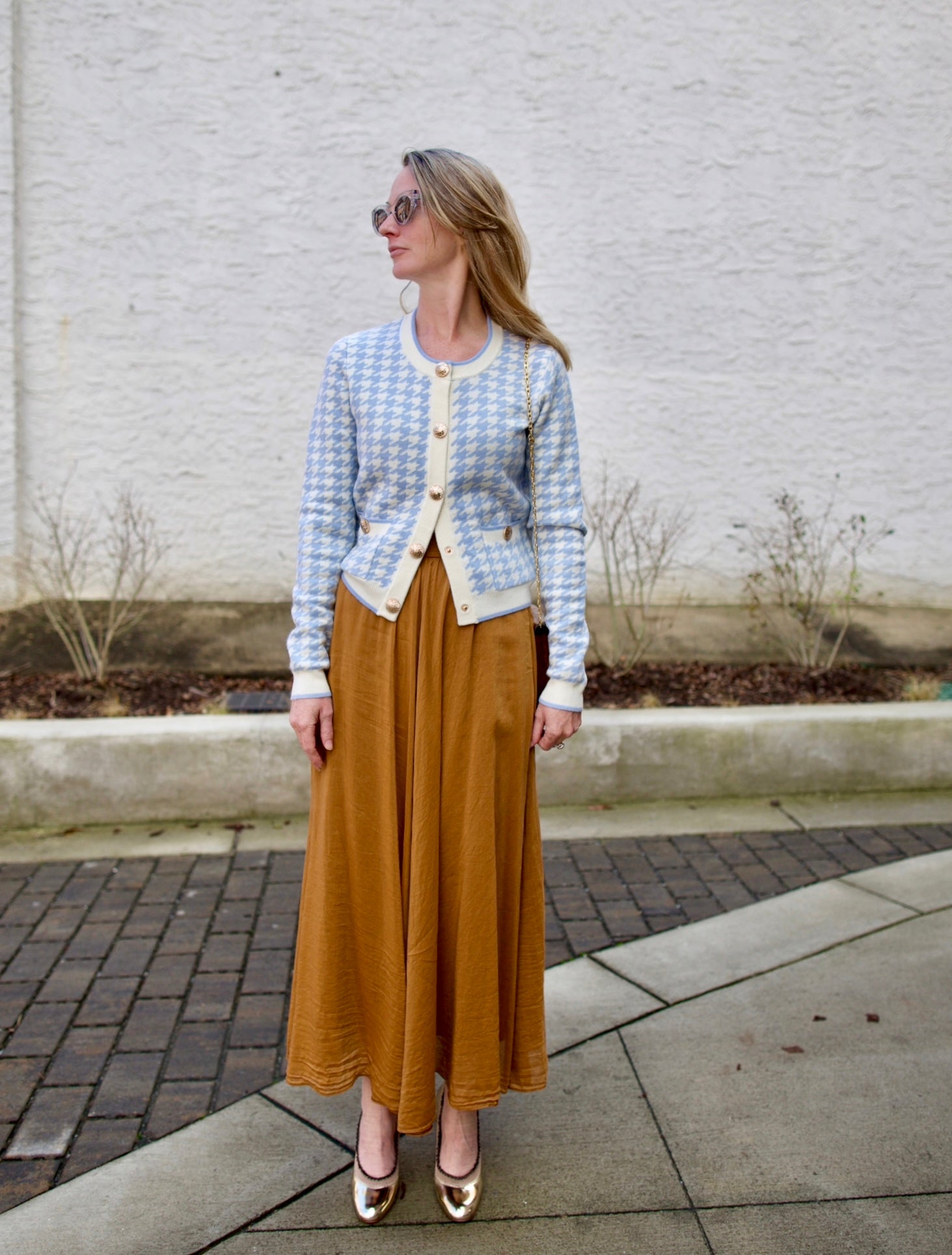 close up image of a woman wearing the Cara Cara priscilla cardigan and forte forte skirt with the Ulla Johnson ruffle pumps