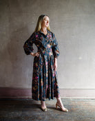 Image featuring a woman wearing the cotton Raya dress by Cara Cara with a collar and button front with full sleeves and flowy skirting in Blue Vintage Blossom print.