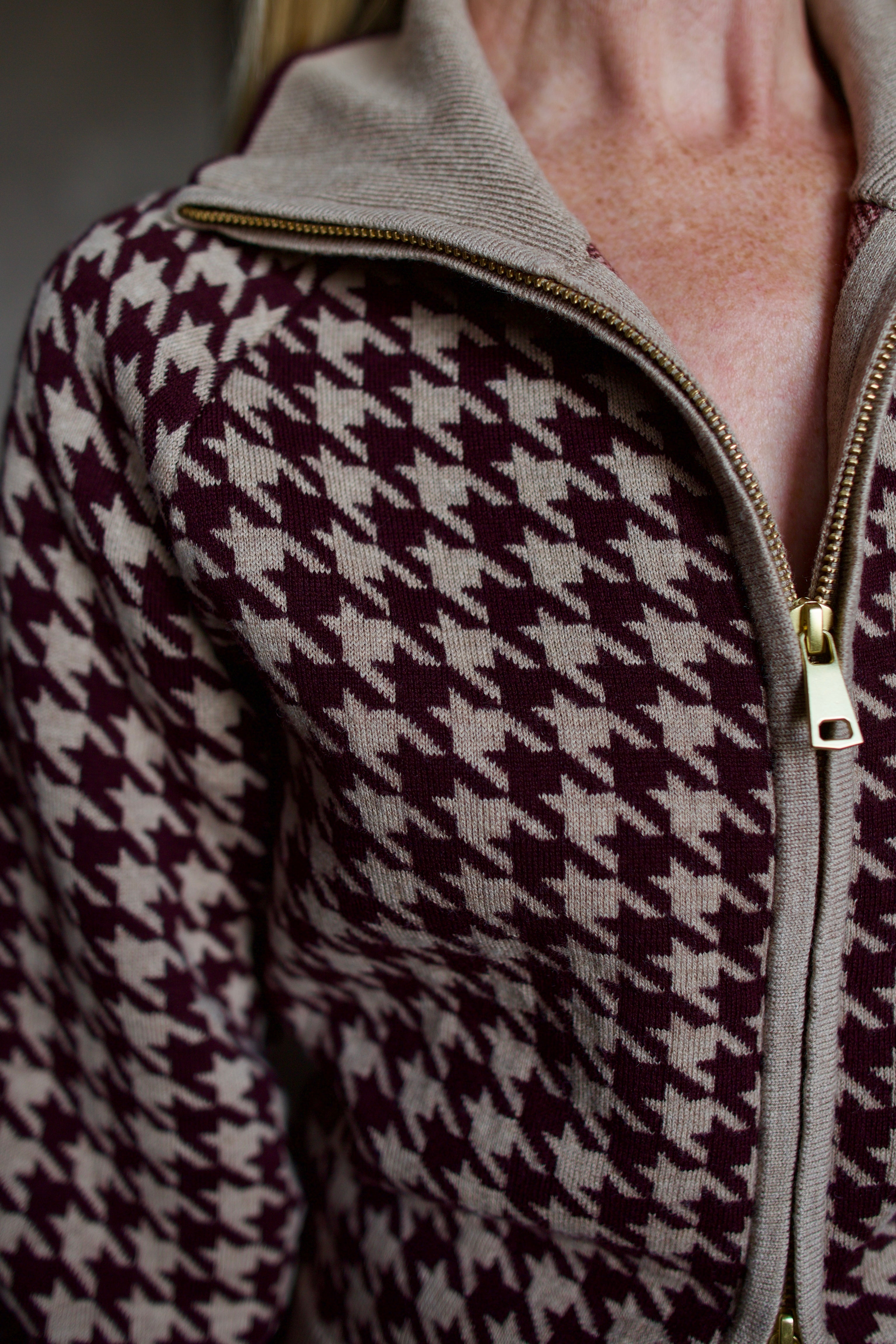 Model wearing a houndstooth patterned fine merino wool Lyss zip up layering sweater by Cara Cara