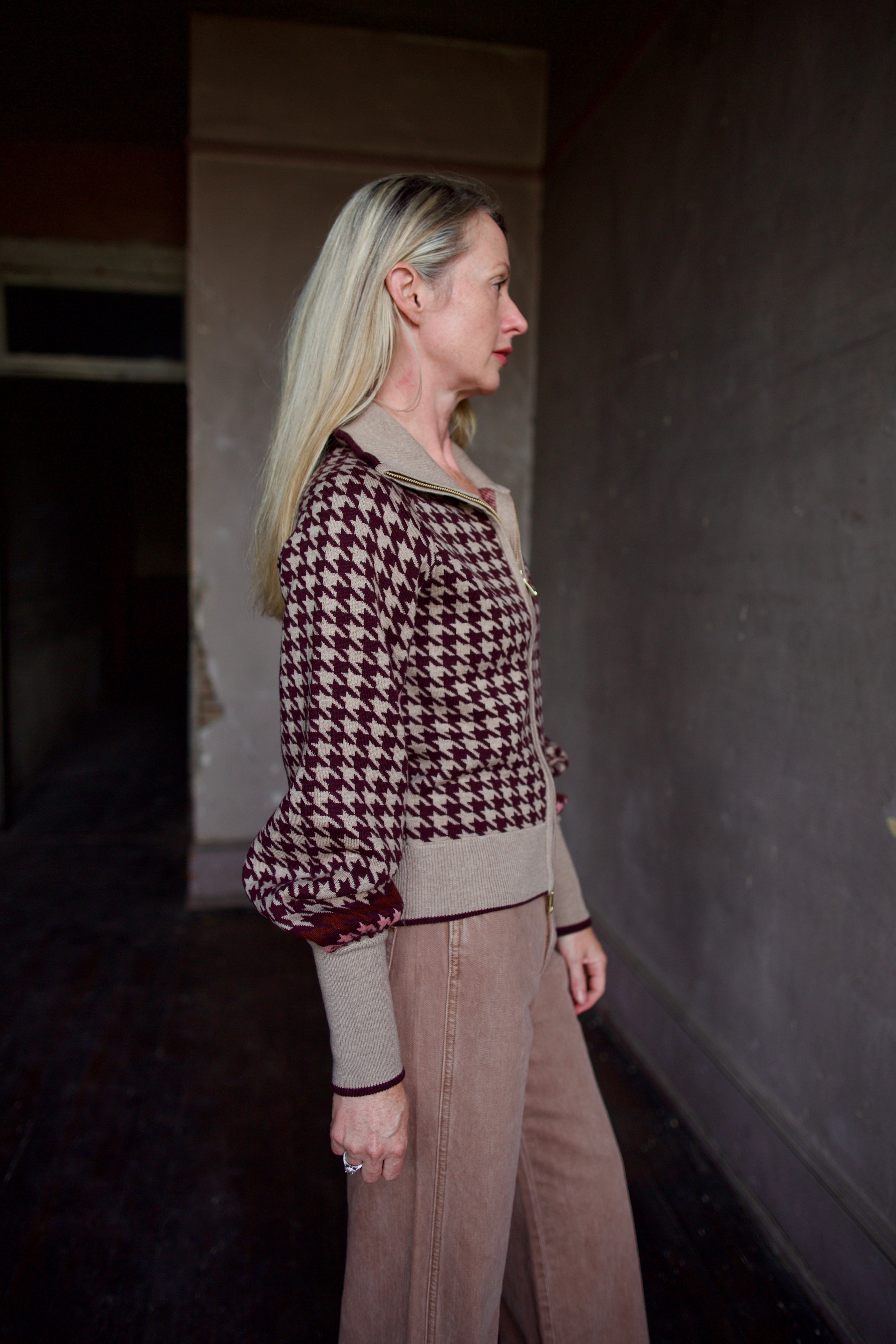 Model wearing a houndstooth patterned fine merino wool Lyss zip up layering sweater by Cara Cara