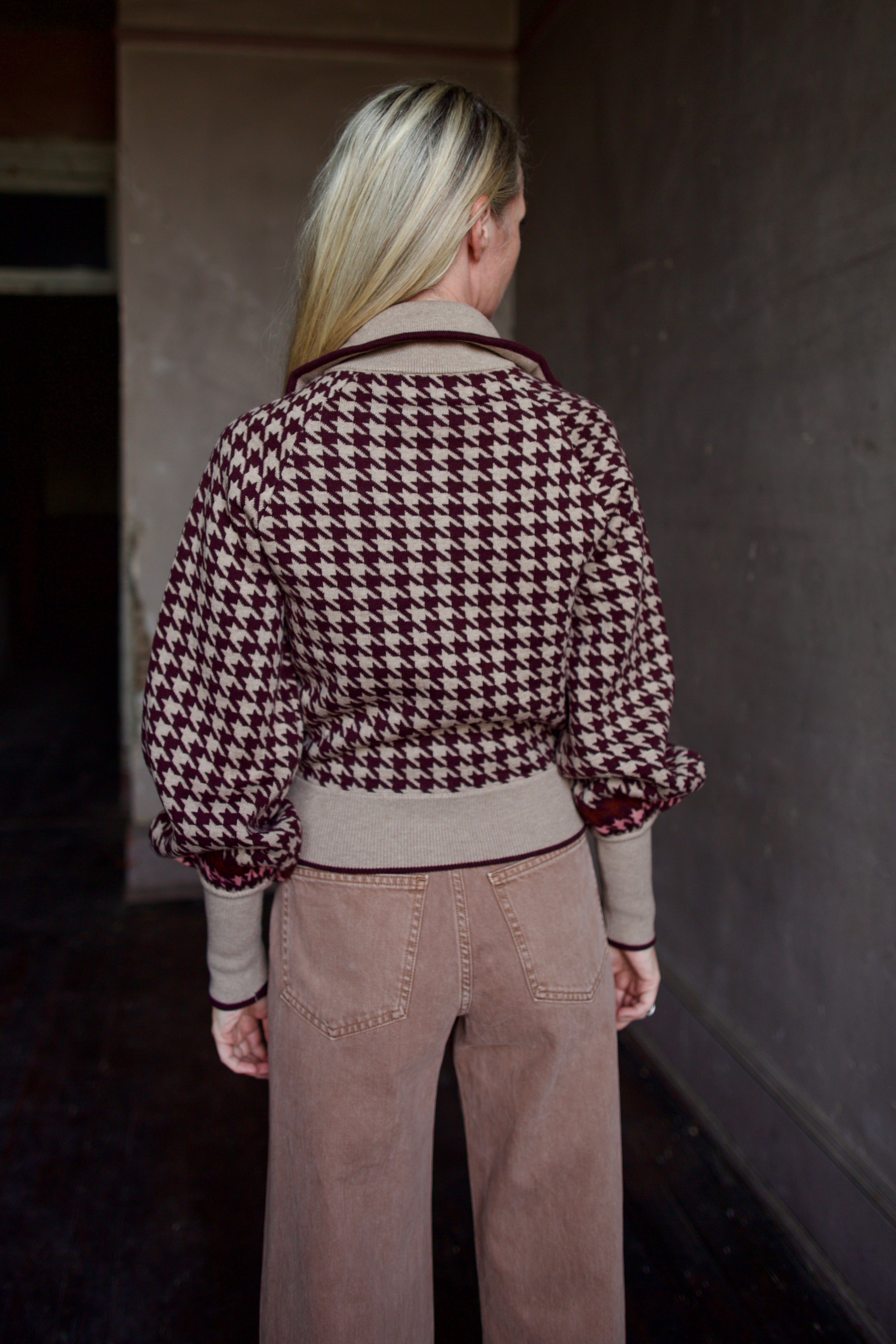 Model wearing a houndstooth patterned fine merino wool Lyss zip up layering sweater by Cara Cara