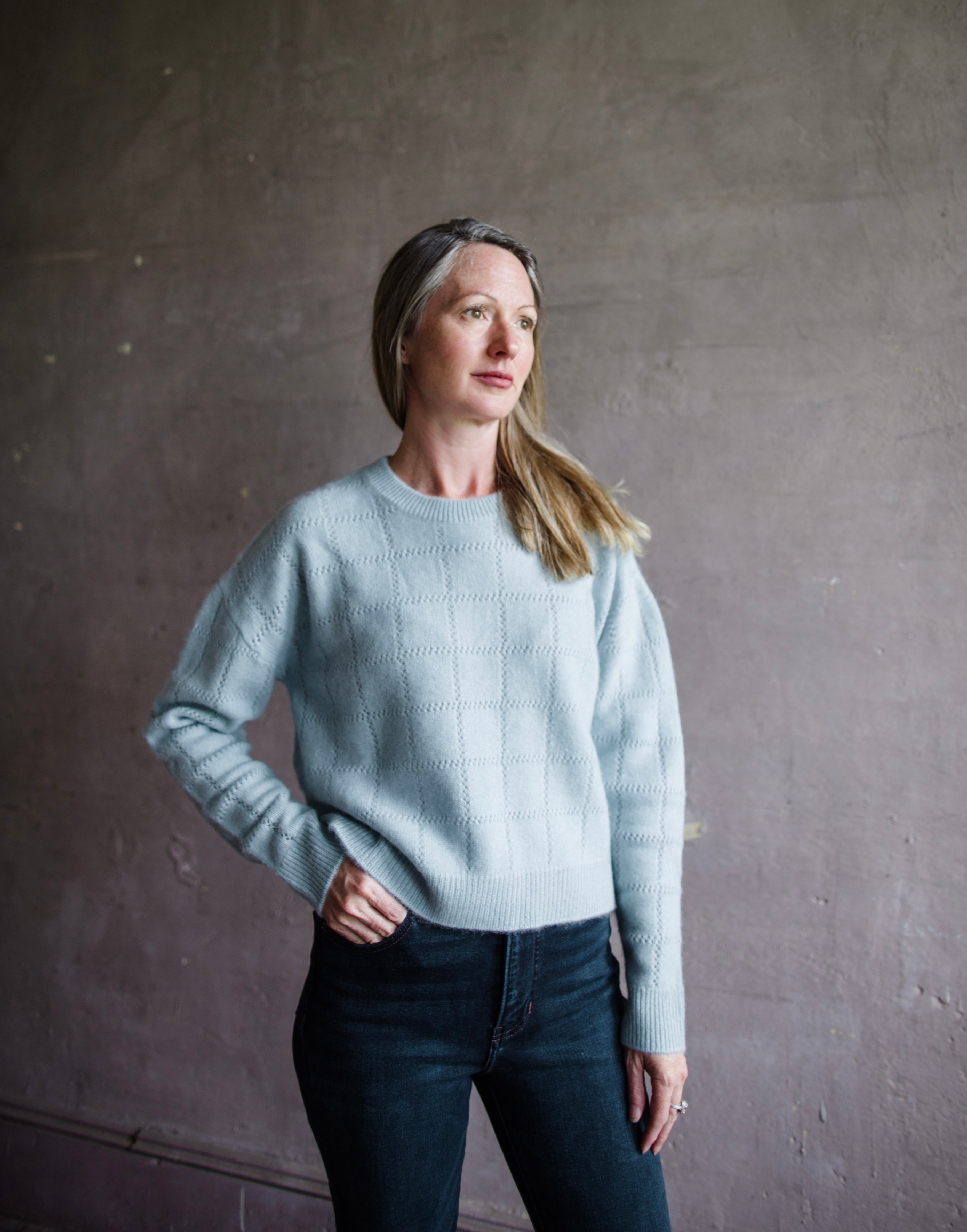 Image featuring a woman wearing the blue cashmere sweater by Naadam with a crew neckline, crochet detailing and a relaxed fit.