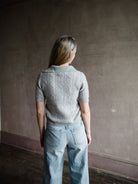 Image featuring a woman wearing a grey cashmere sweater by Naadam with a v neckline and collar as well as a cable knit texture in tailored fit.