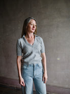 Image featuring a woman wearing a grey cashmere sweater by Naadam with a v neckline and collar as well as a cable knit texture in tailored fit.