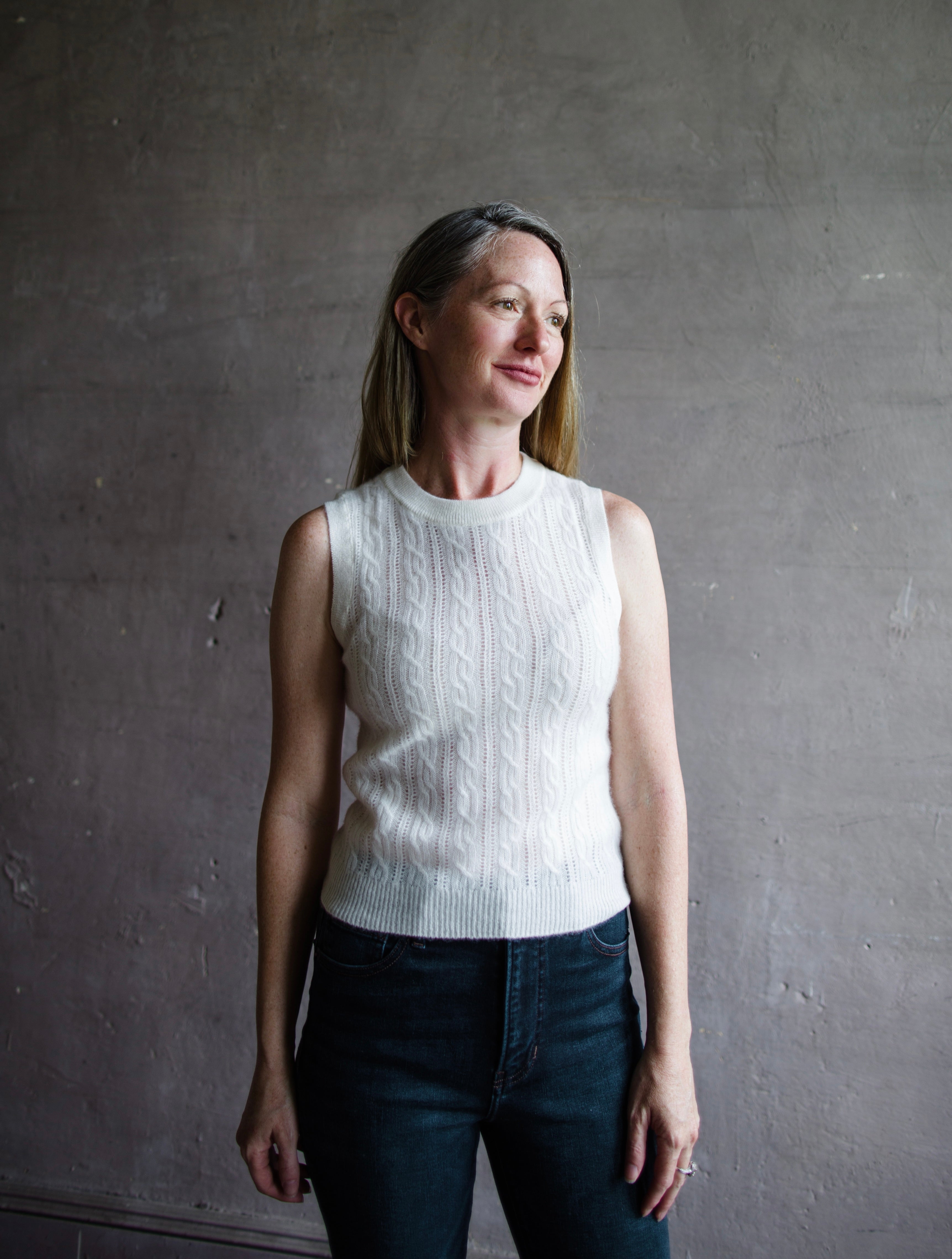 Image featuring a woman wearing a cream sweater by Naadam with a crew neckline and soft cable knit texture in a slightly tailored fit.