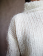 Close up view of woman wearing Brazeau Tricot Charlotte’s web topper in shade ivory alpaca blend