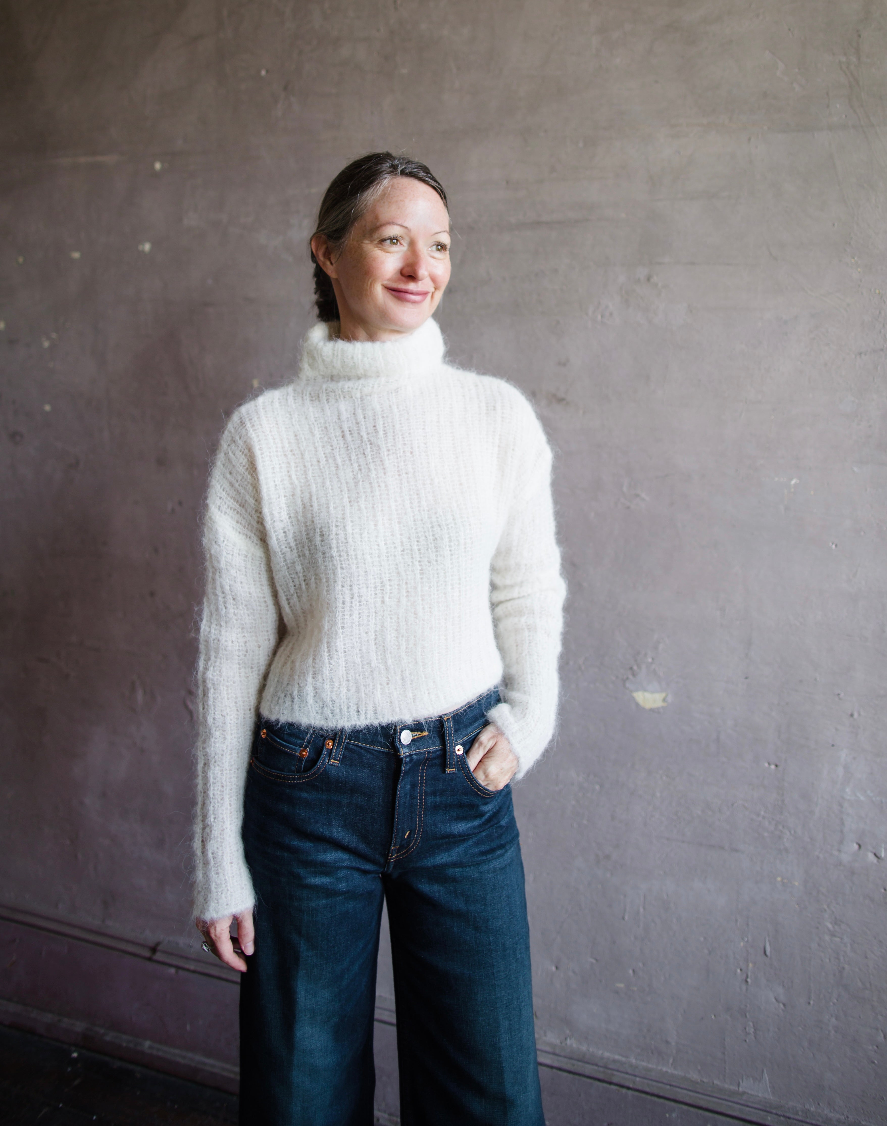 Front view of woman wearing Brazeau Tricot Charlotte’s web topper in shade ivory alpaca blend