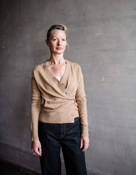 Image featuring a woman wearing the almond cashmere sweater by Cissa with a button front than can be worn multiple ways- crossed over or as a cardigan.