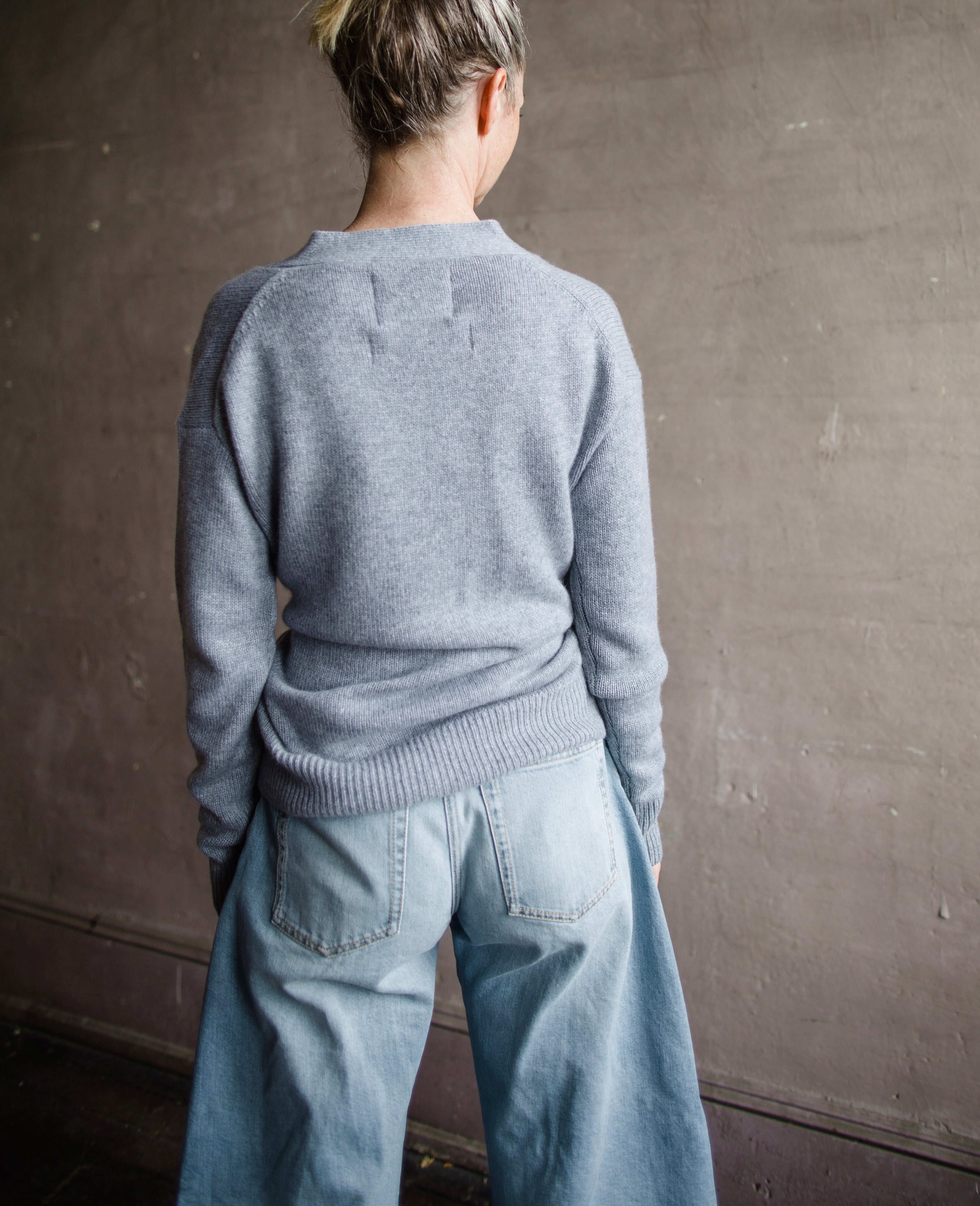 Image featuring a woman wearing the grey cashmere sweater by Cissa with a button front than can be worn multiple ways- crossed over  or as a cardigan.