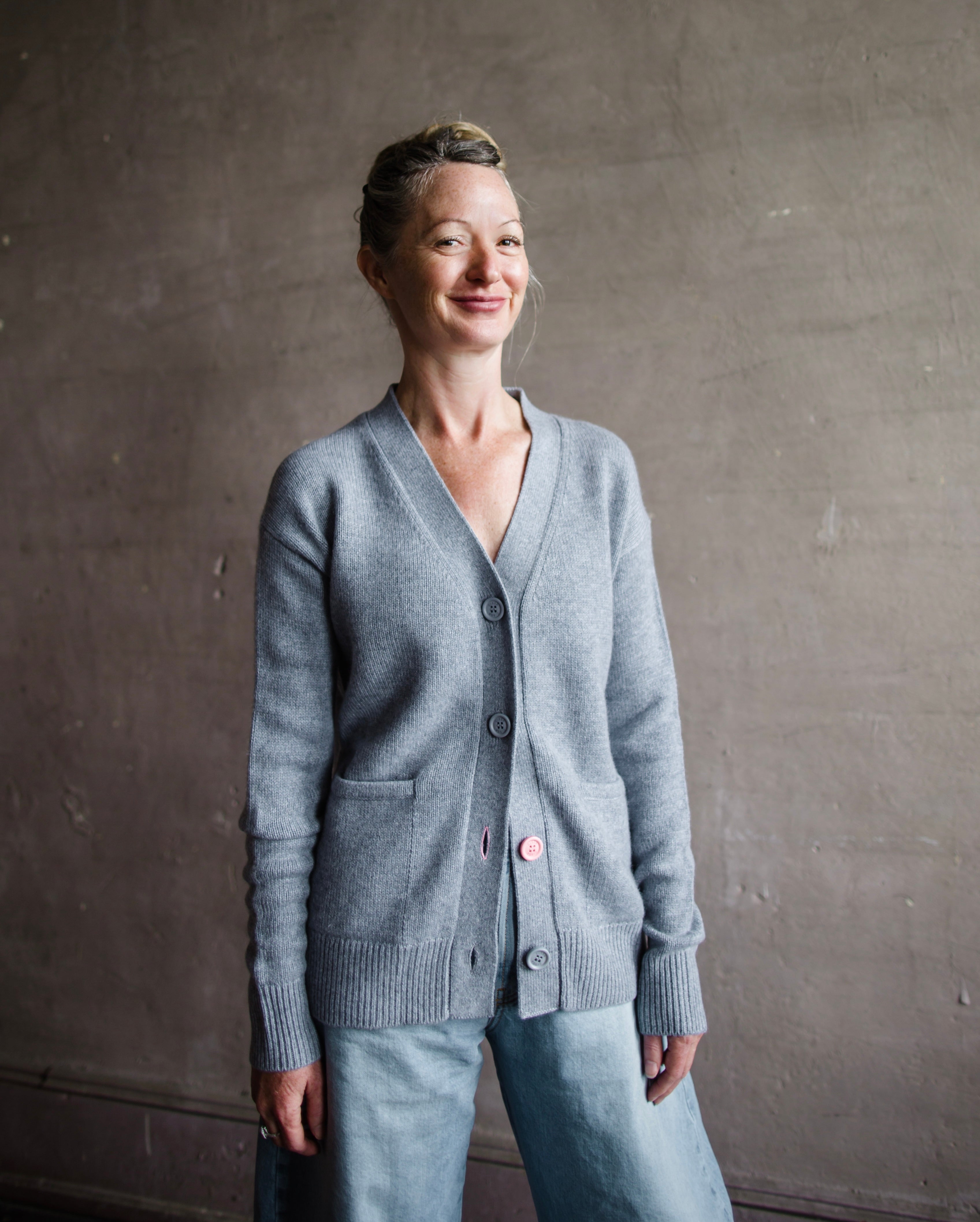 Image featuring a woman wearing the grey cashmere sweater by Cissa with a button front than can be worn multiple ways- crossed over  or as a cardigan.