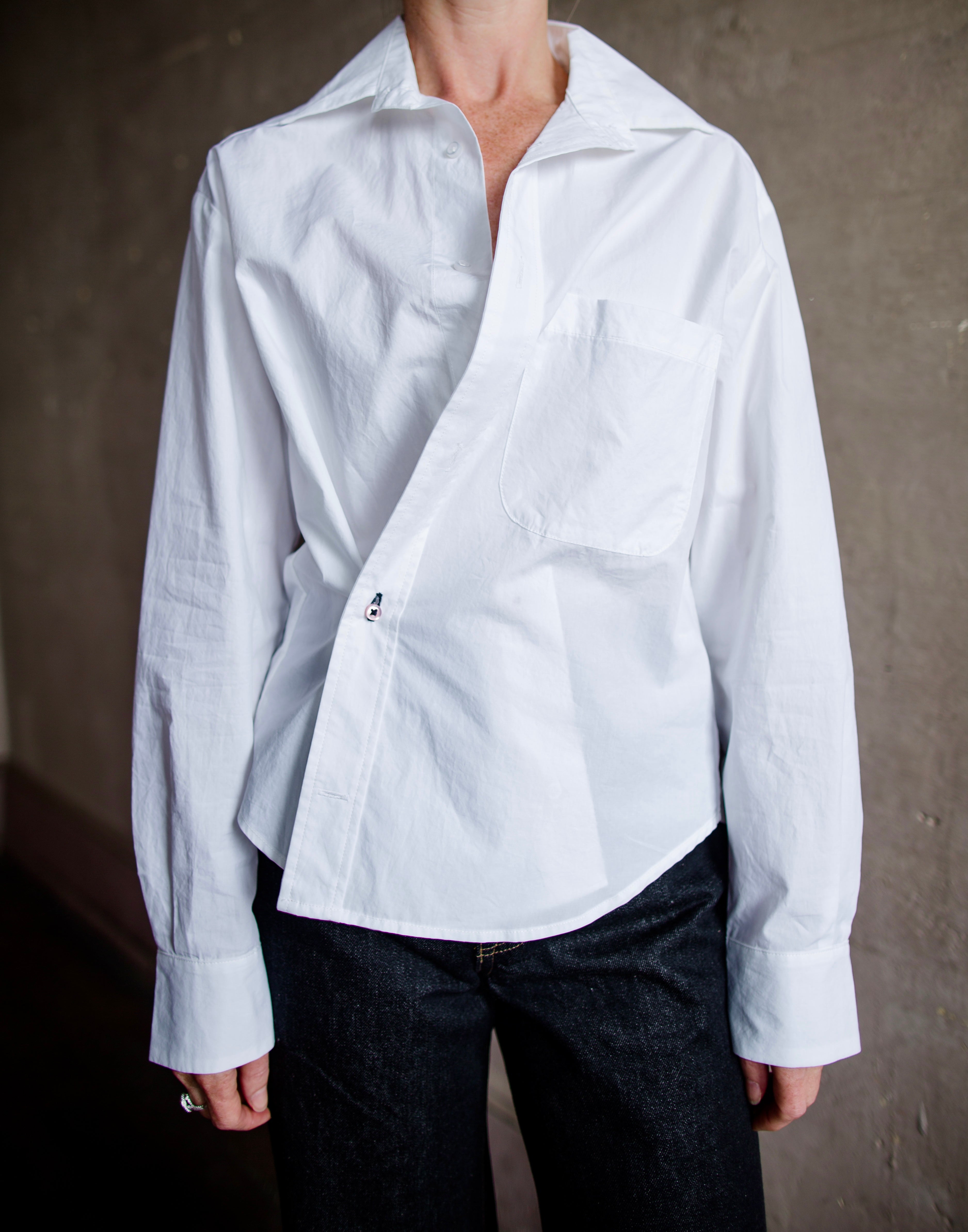 Image of a woman wearing the white cotton twist top by Cissa with a button front that can be worn multiple ways- buttoned across the waist or straight down.